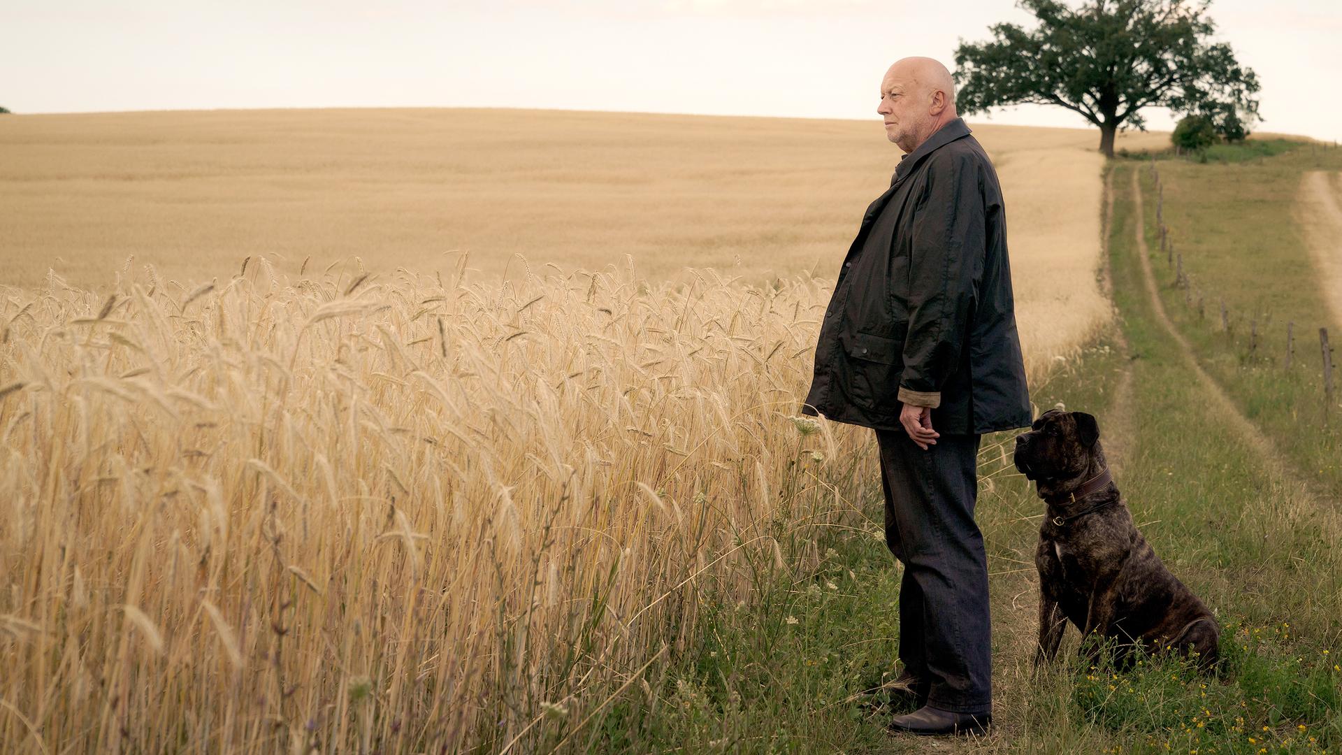 Rudolf Gombrowski steht mit seinem Hund vor den Feldern.