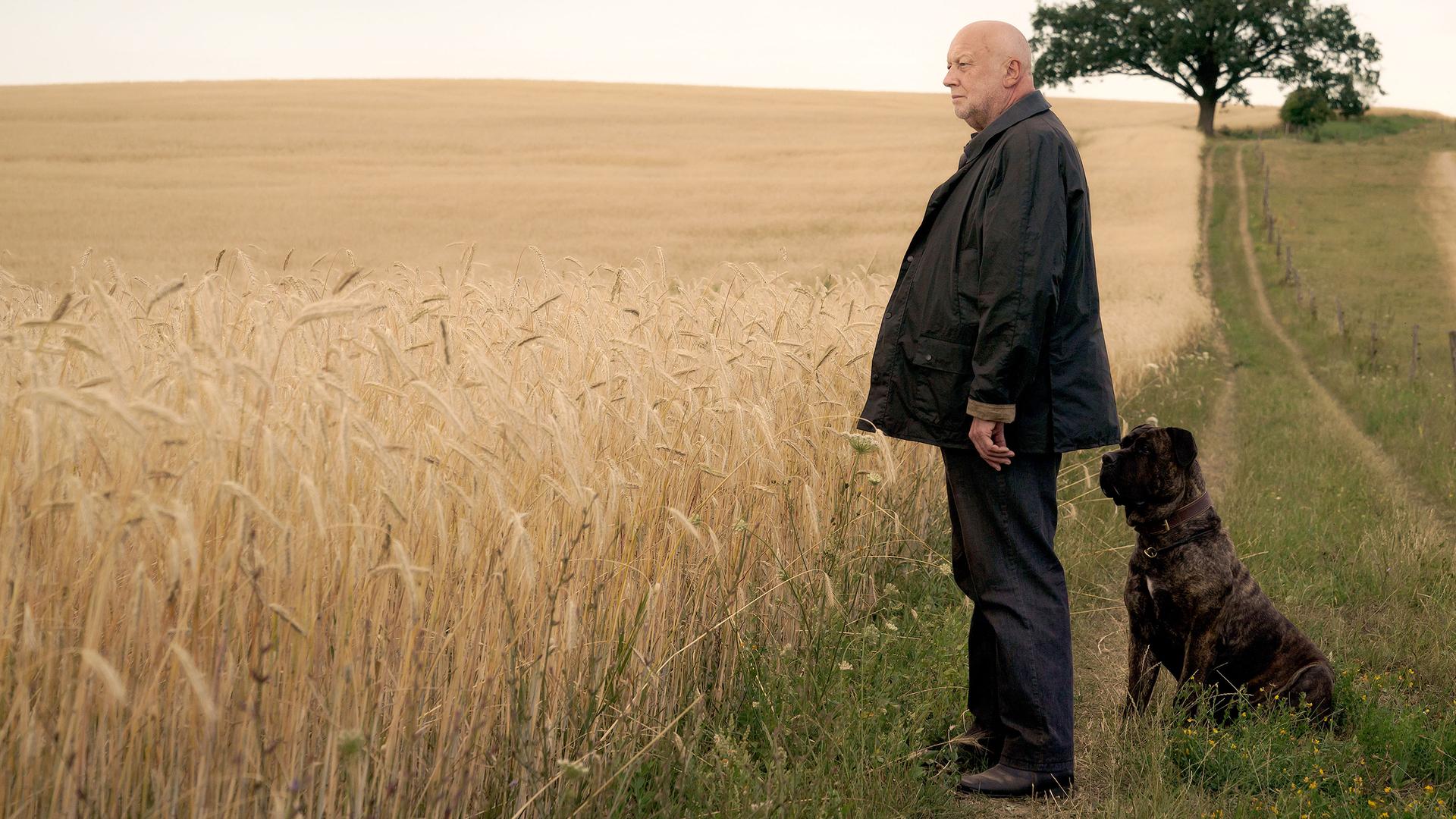 Rudolf Gombrowski steht mit seinem Hund vor den Feldern.