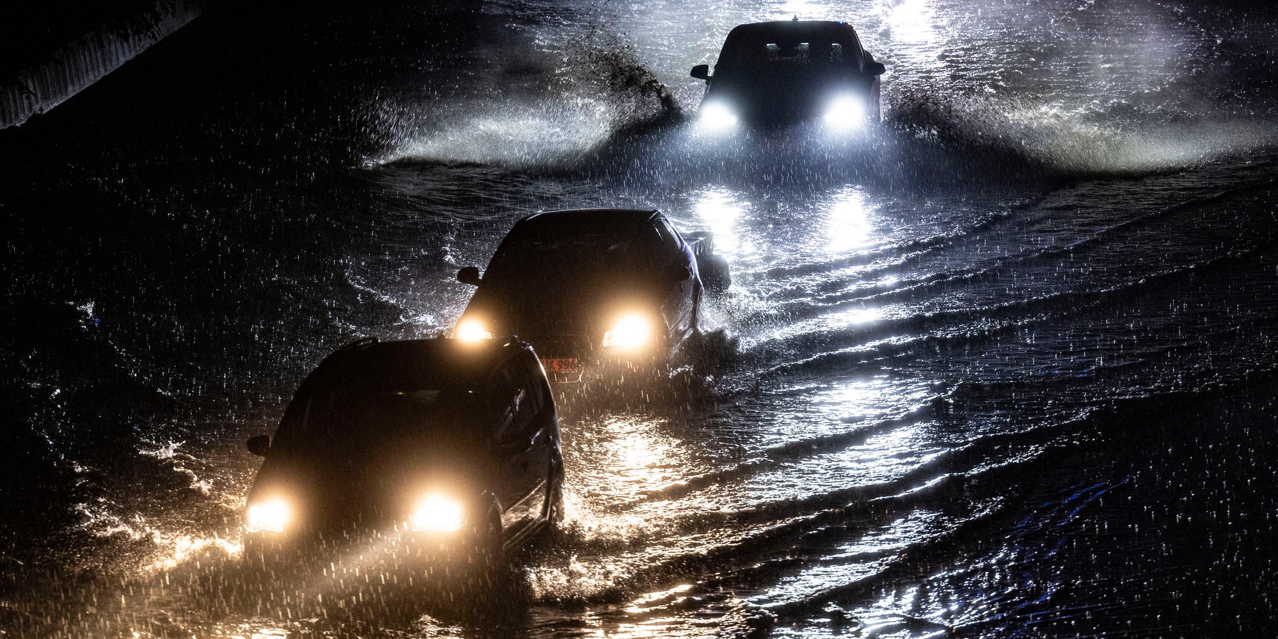 Teilabschnitte der Autobahn A59 in Duisburg sind am Abend nach stundenlangen Regenfällen überschwemmt, Autos fahren durch die Wassermassen.