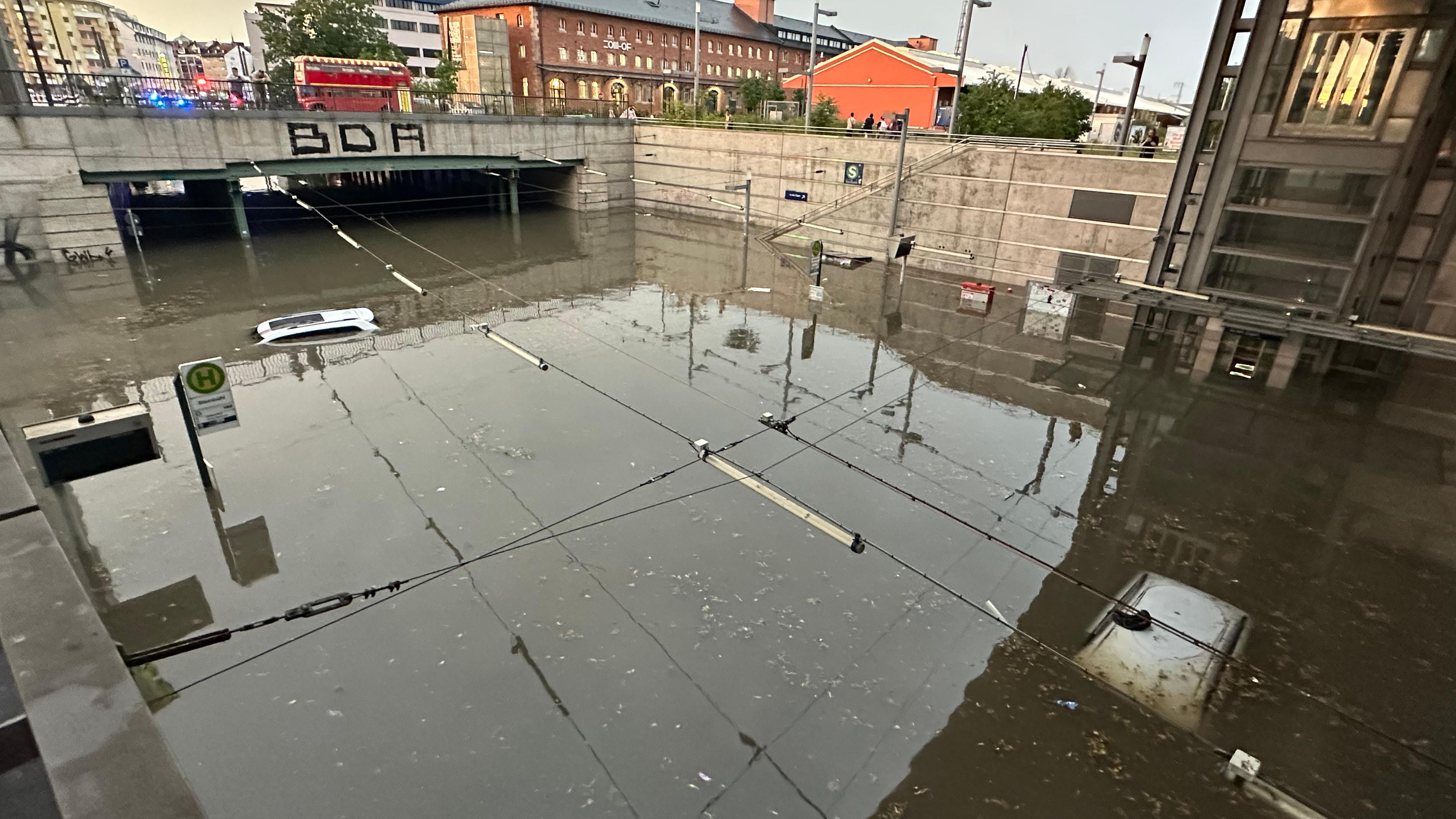 Autos, von dem man jeweils nur das Dach erkennen kann, steht in einer überschwemmten Straße an einer Unterführung nach Unwetter in Nürnberg
