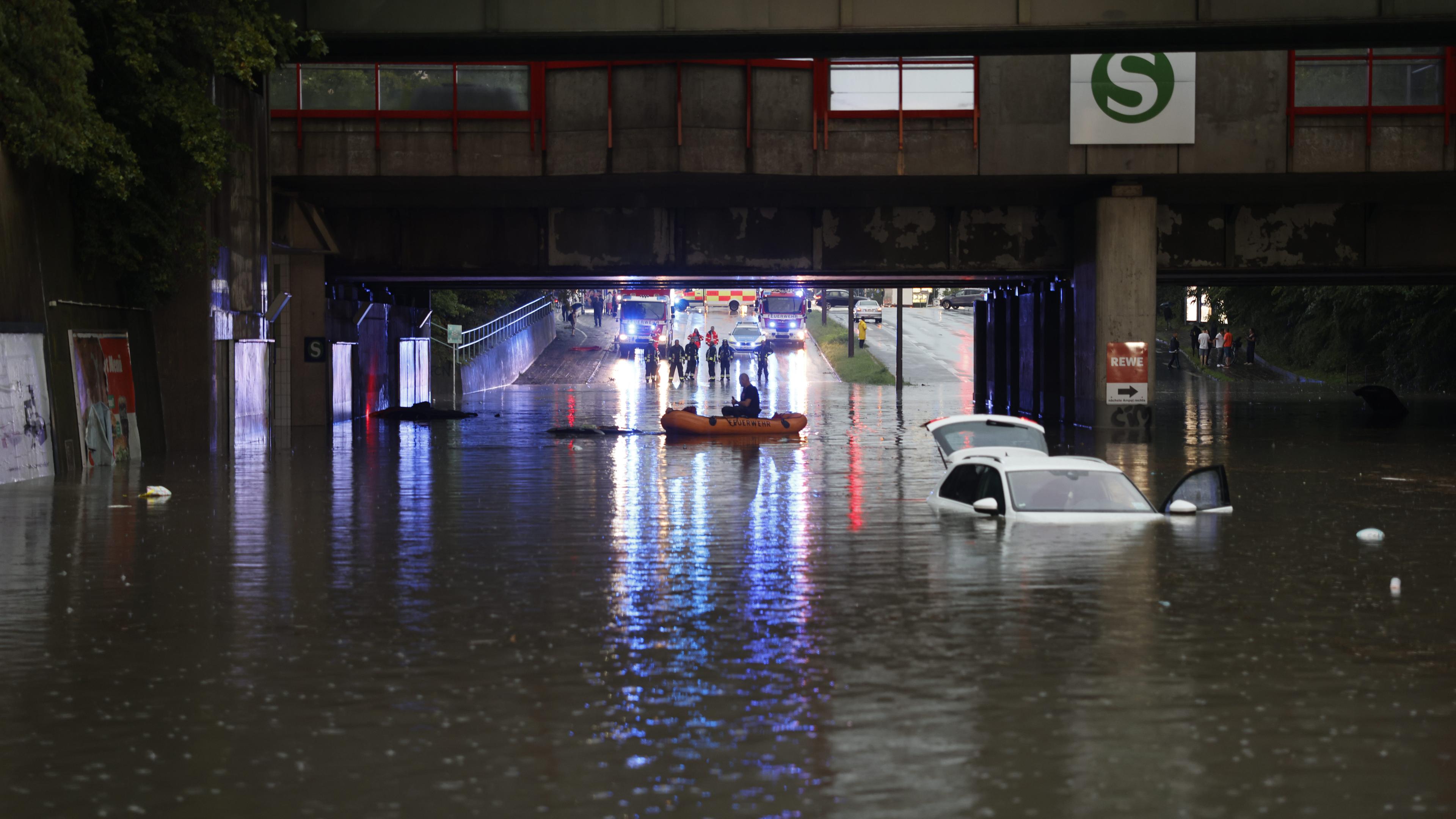 Einsatzkräfte der Feuerwehr können nur noch mit einem Schlauchboot zu den Autos in einer überschwemmten Unterführung gelangen. 