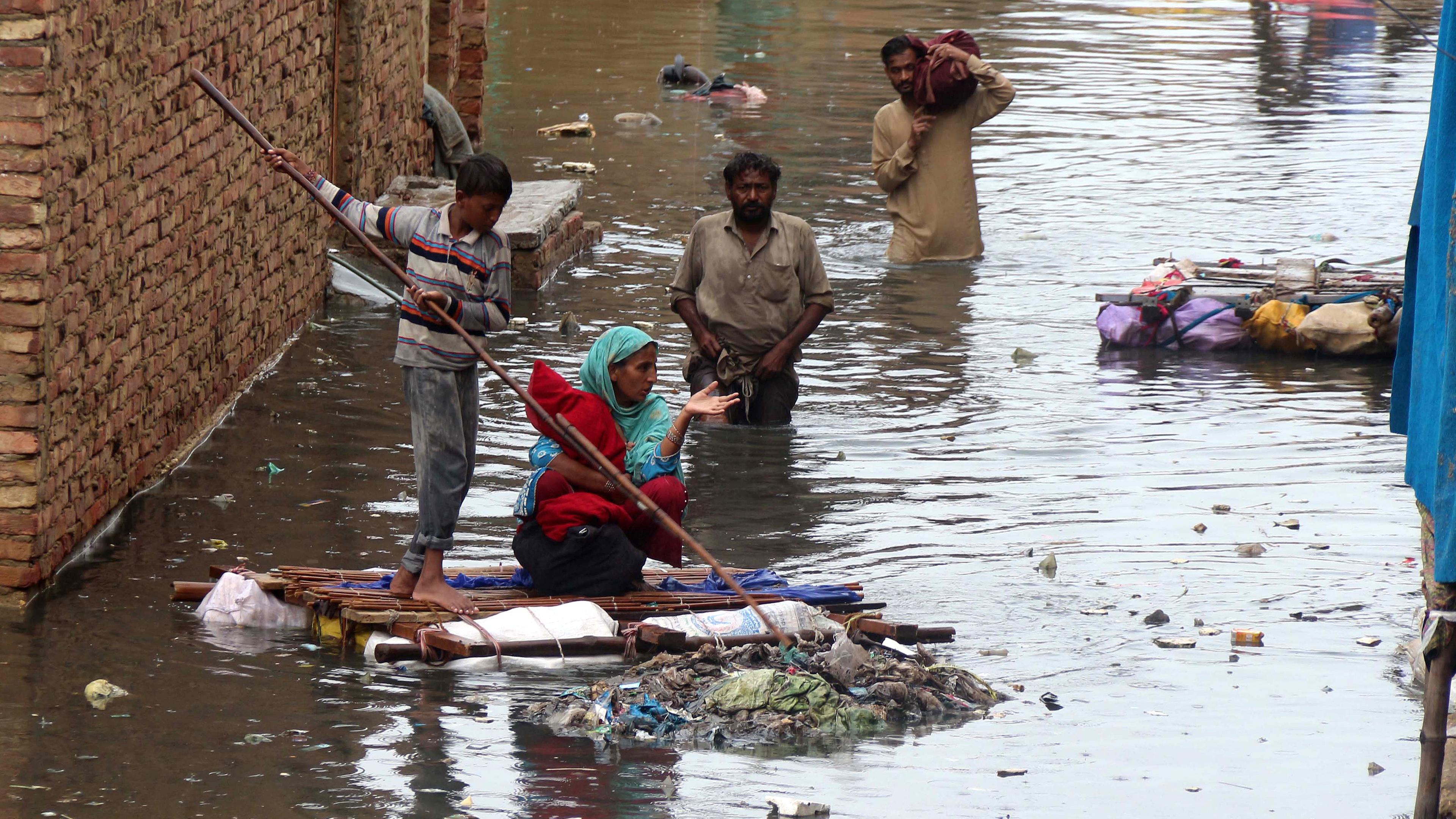 Zwei Männer, ein Junge und eine Frau laufen durch die überfluteten Straßen von Hyderabad.