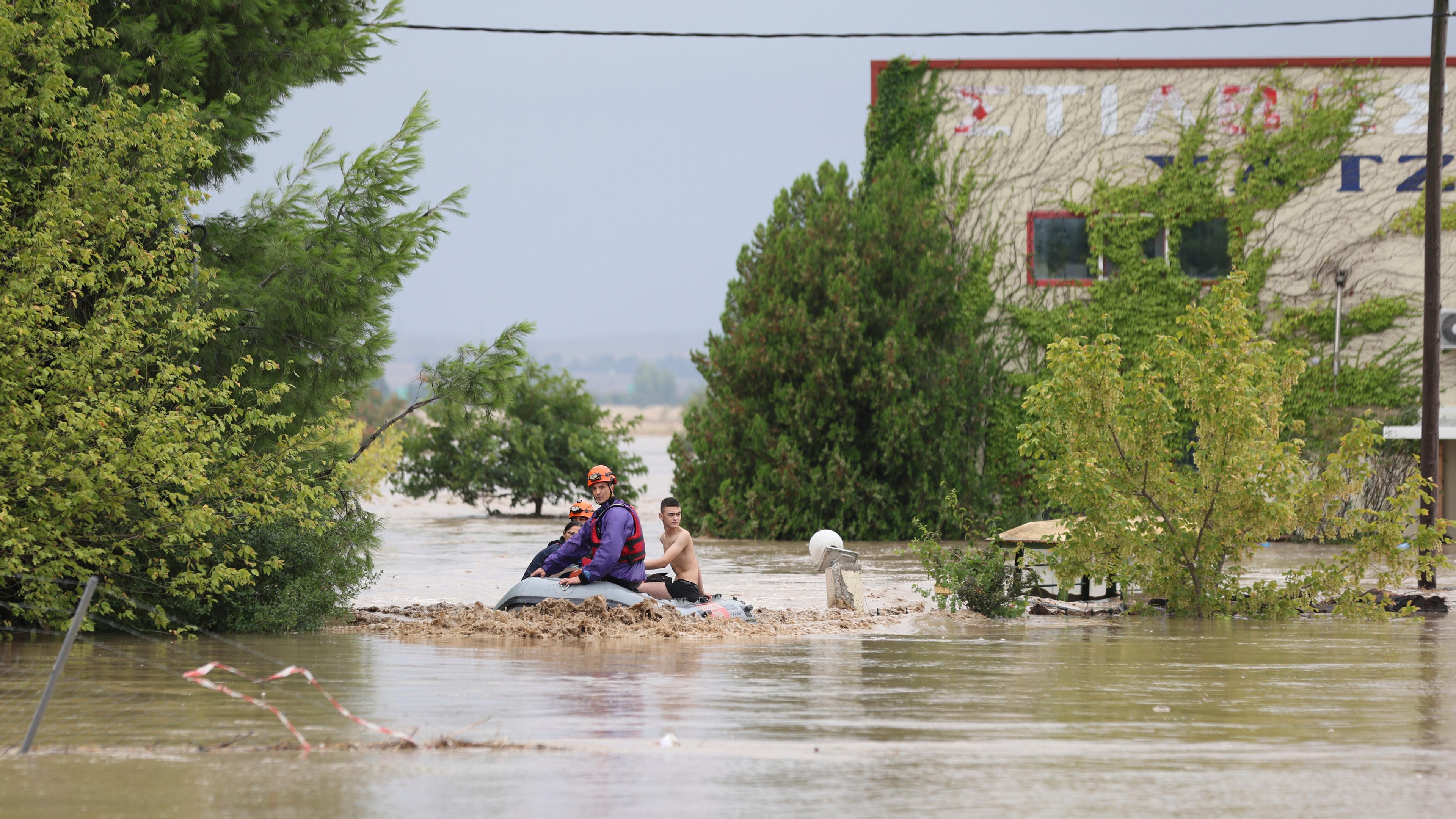 06.09.2023, Griechenland, Larissa: Feuerwehrleute mit einem Schlauchboot evakuieren Menschen aus einem überfluteten Gebiet. 