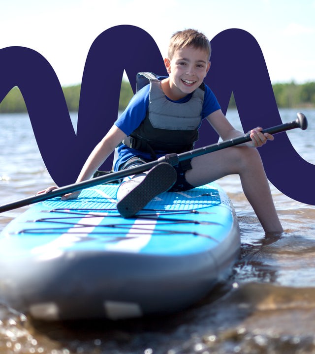 Endrik Schmid (11) sitzt am Strand vom Senftenberger See auf einem SUP-Board