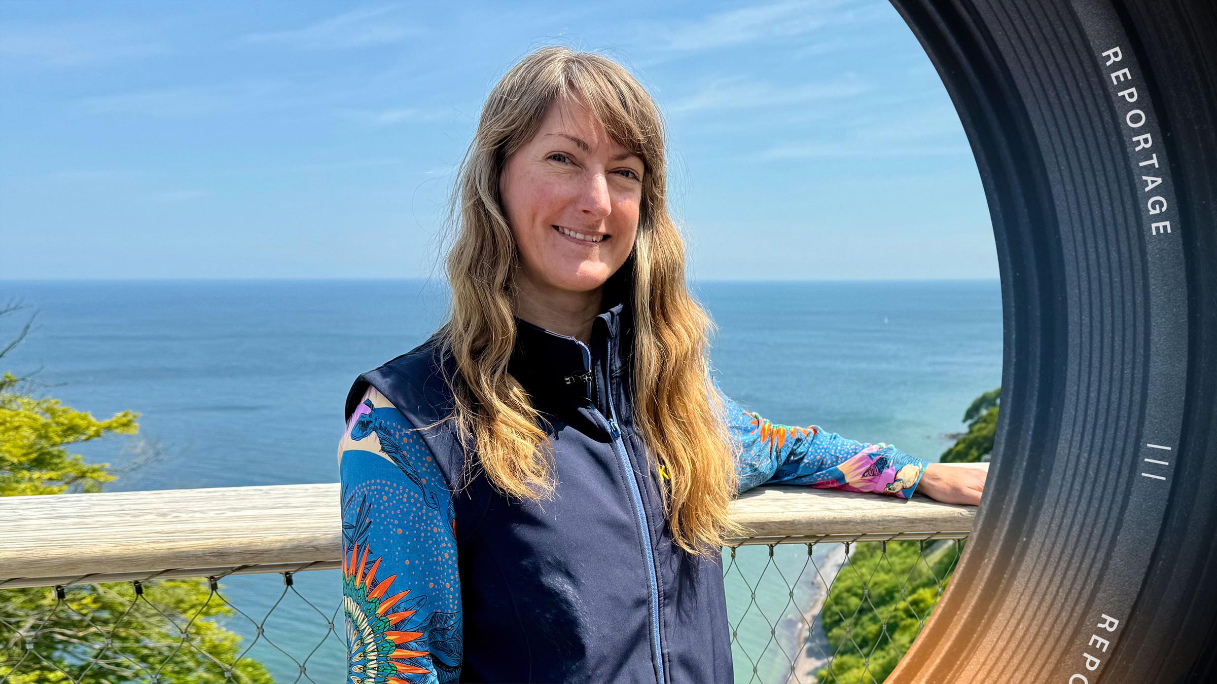 Eine Frau steht am Geländer über den Kreidefelsen, hinter ihr liegt das Meer.