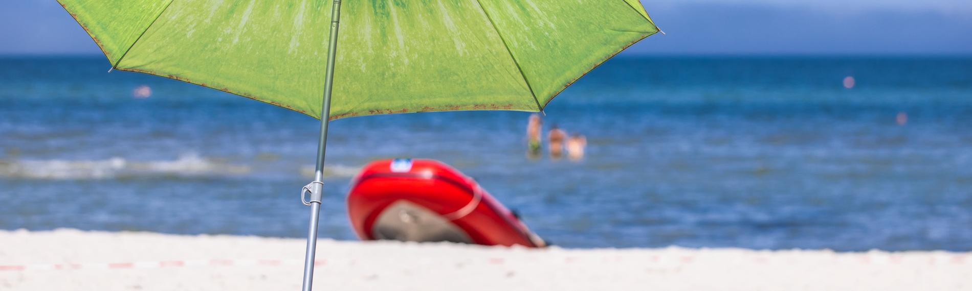 Ein großer Sonnenschirm steht am Strand an der Ostseeküste.
