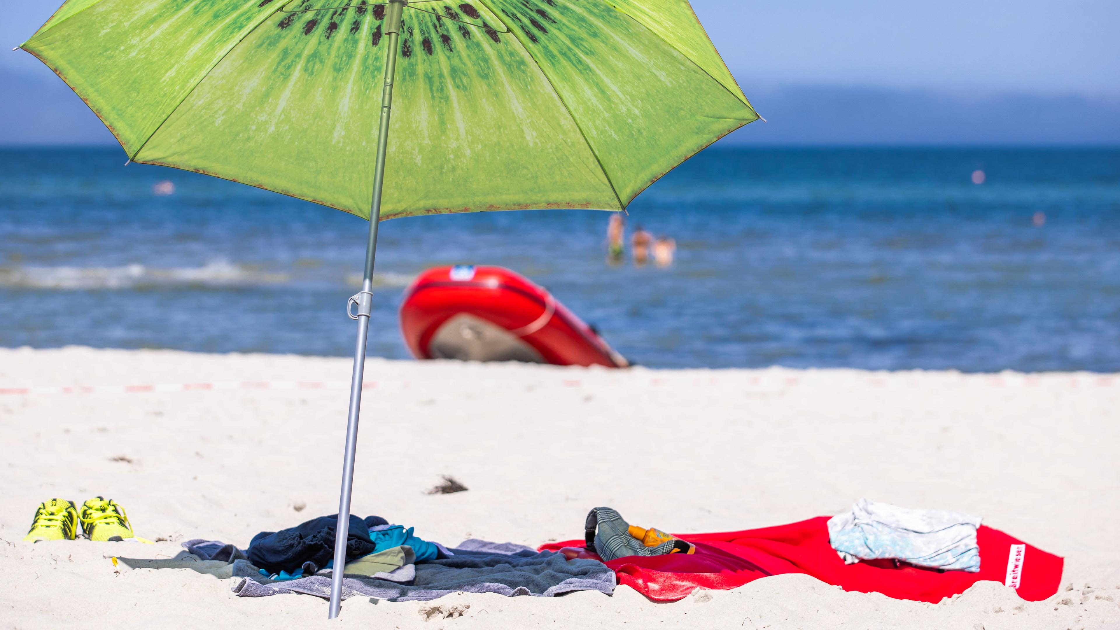 Ein großer Sonnenschirm steht am Strand an der Ostseeküste.