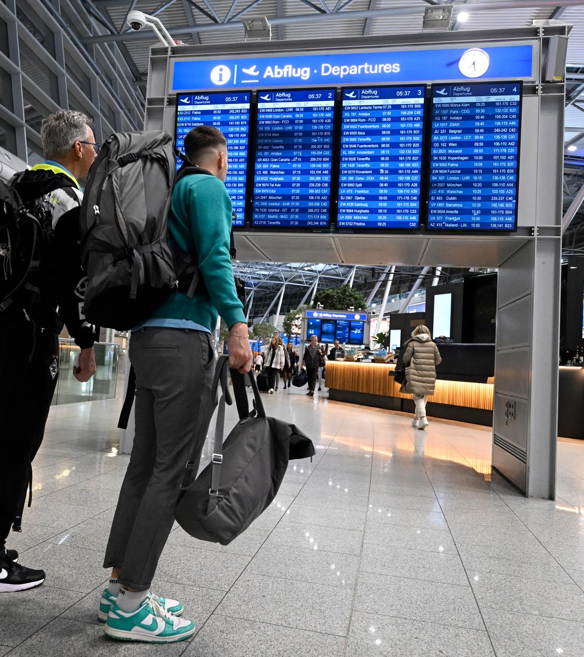 Reisende schieben ihre Koffer am Flughafen Düsseldorf zur Gepäckaufgabe.