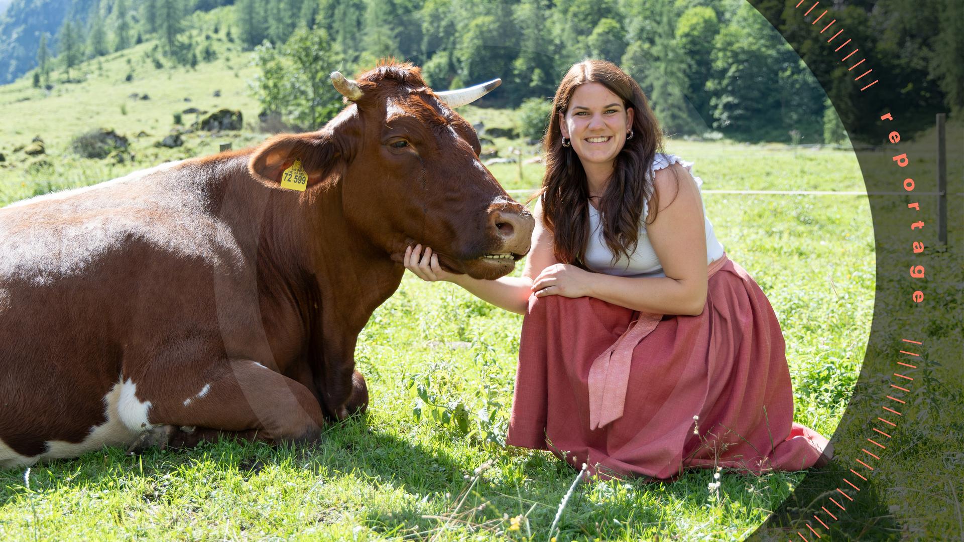 Veronika hockt neben einer liegenden Kuh auf einer Weide und schaut lächelnd in die Kamera.