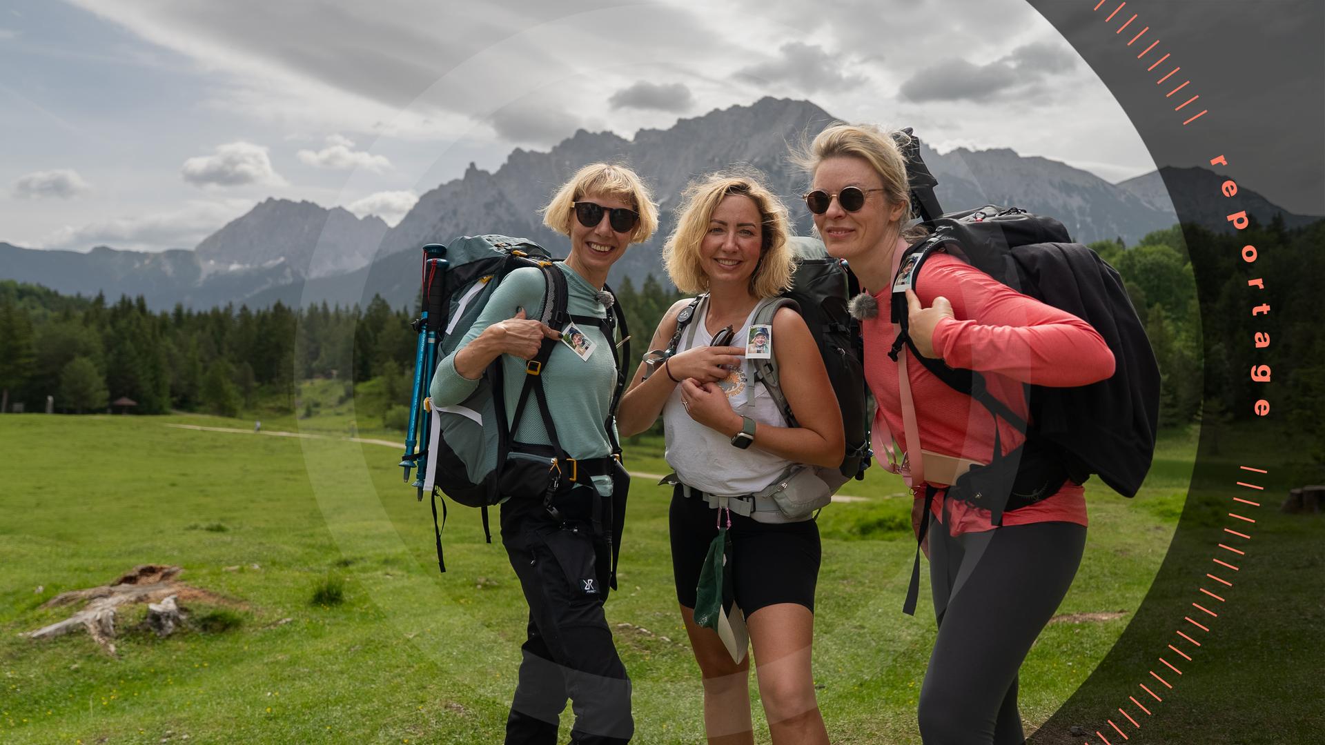 Die Freundinnen Revi, Annika und Claudia stehen nebeneinander auf einer grünen Wiese vor dem Bergpanorama des Karwendelgebirges. Sie schauen lächelnd in die Kamera.