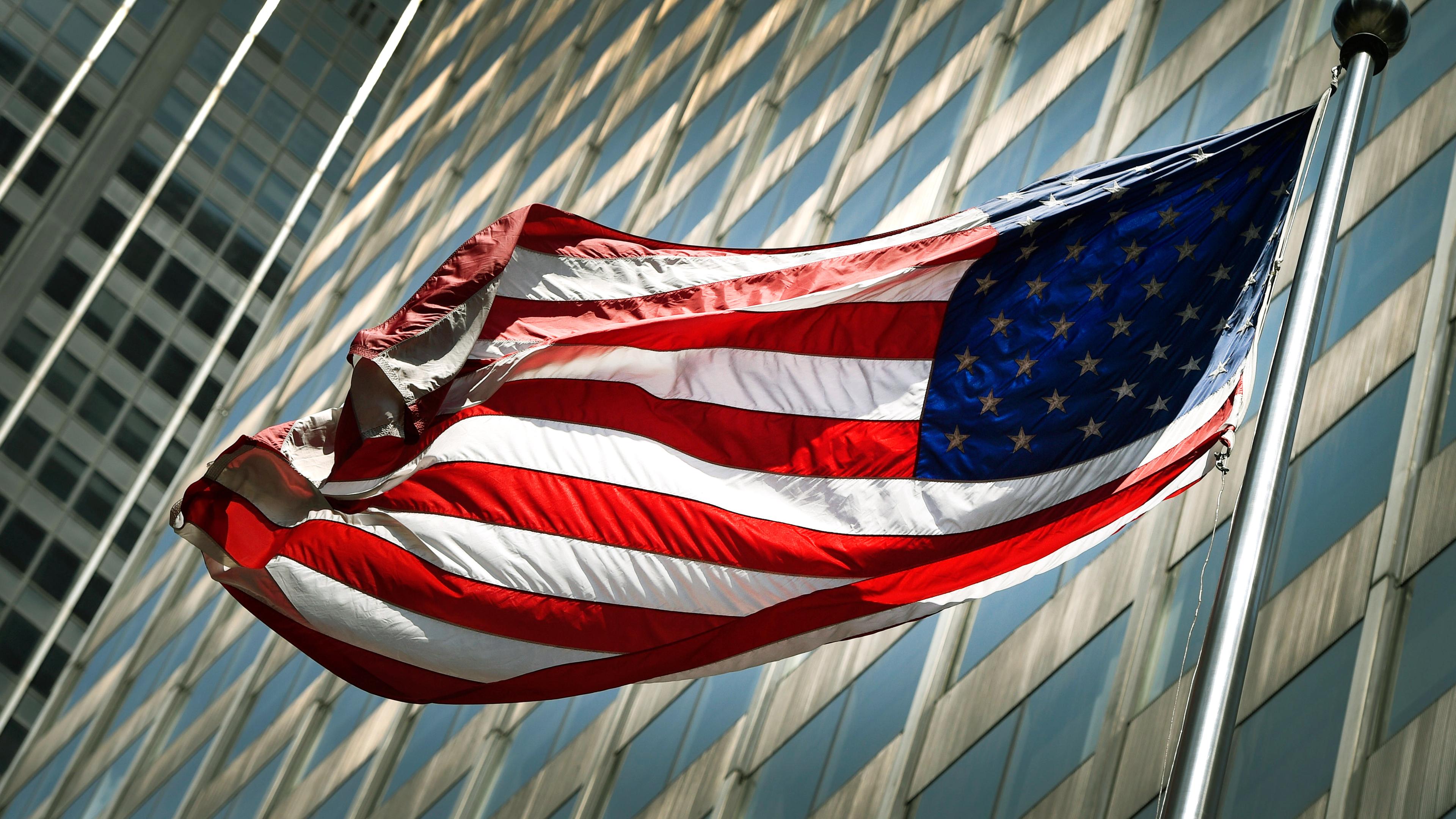US-Flagge vor Büro-Hochhaus