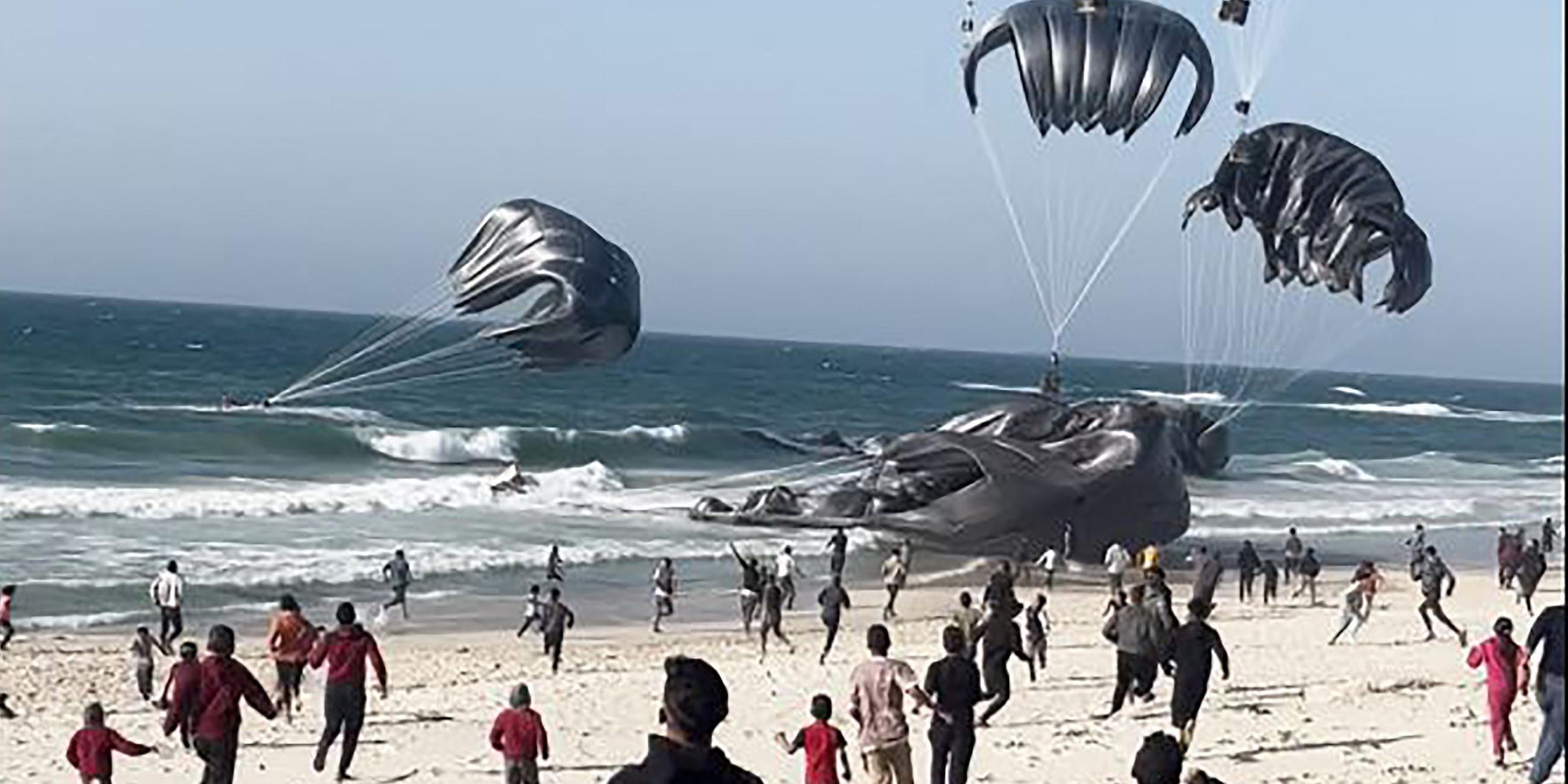 Gazastreifen: Palästinenser rennen auf Fallschirme zu, an denen Lebensmittelpakete befestigt sind.