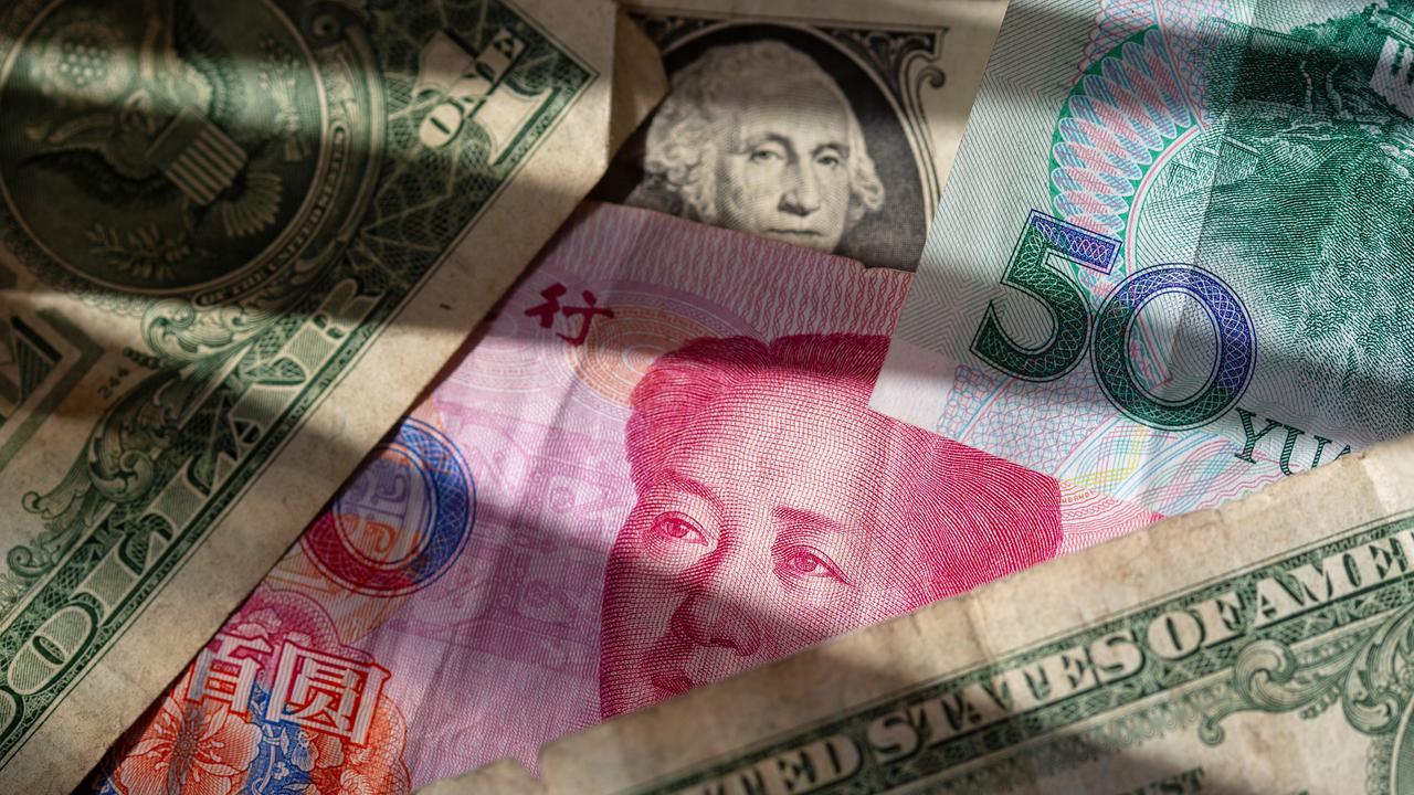 Chinese Yuan banknotes lie between several US dollar signs.