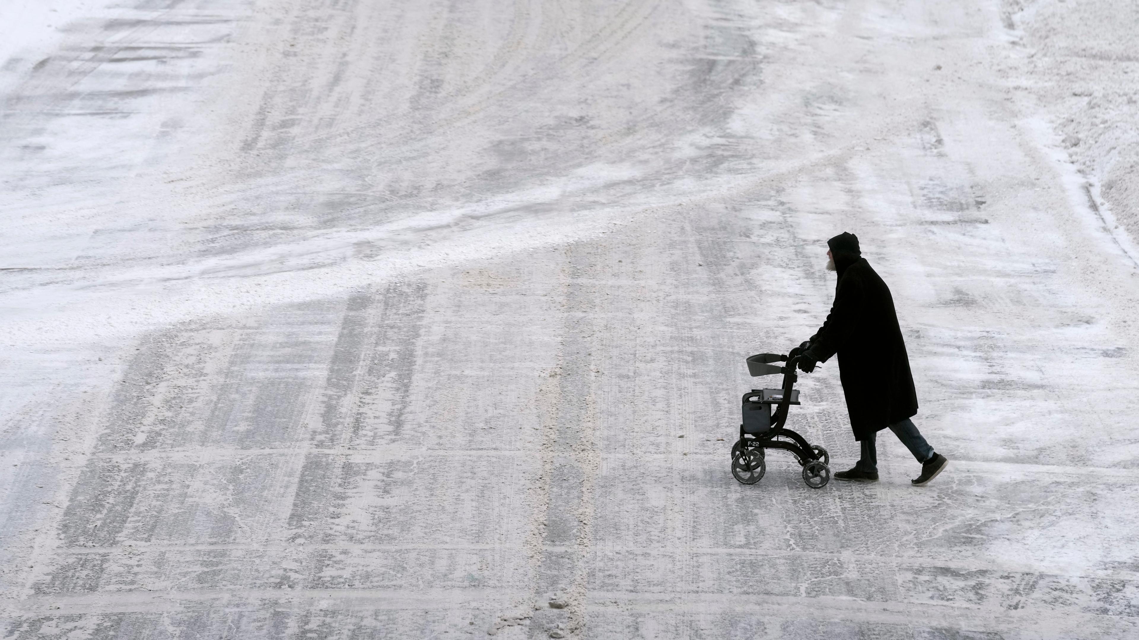USA, Des Moines: Ein Fußgänger überquert eine schneebedeckte Straße in der Innenstadt.