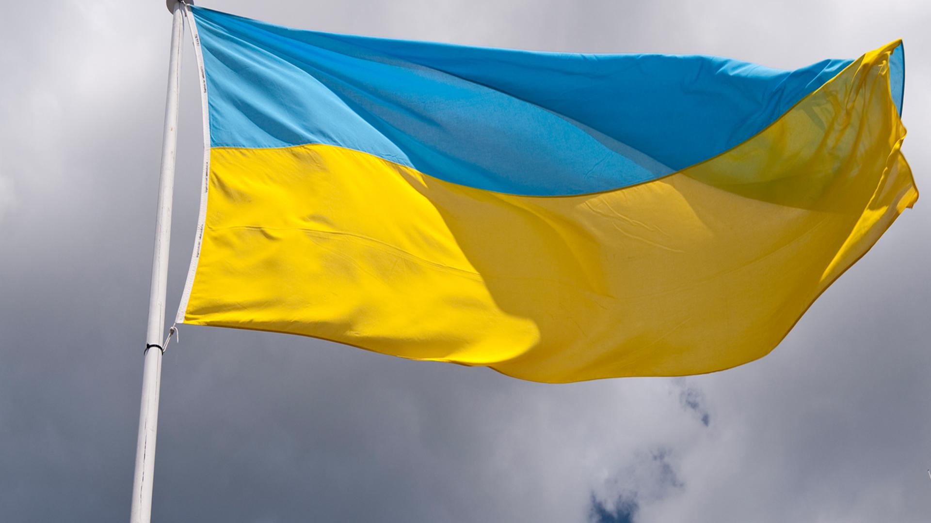 Eine im Wind wehende Ukraine-Flagge vor bewölktem Himmel