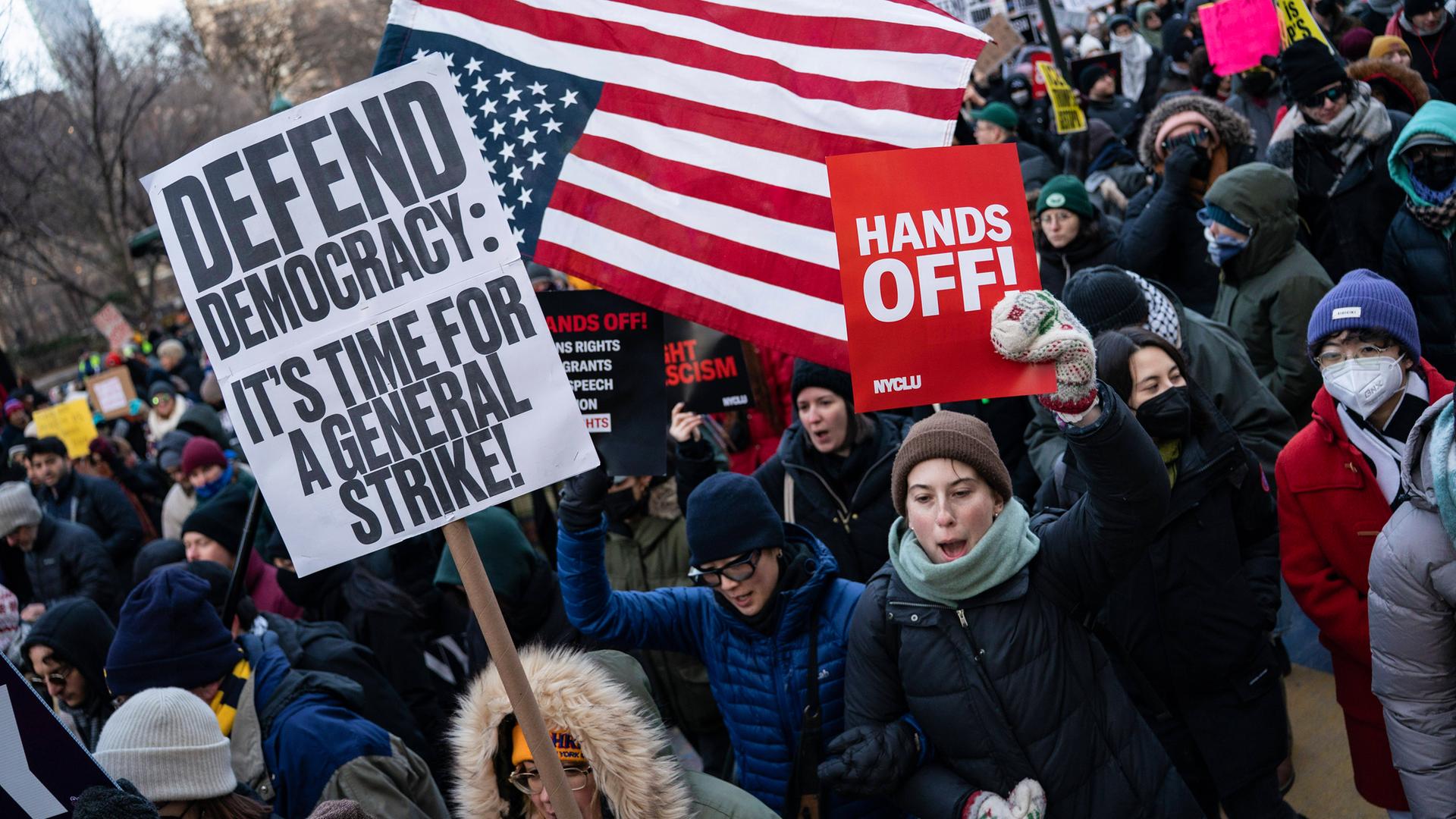 Demonstranten schwenken die US-Flagge und tragen Schilder, auf denen aufgerufen wird, die Demokratie zu verteidigen.