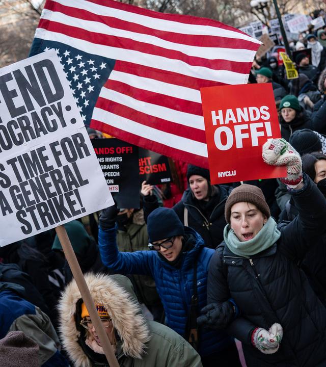 Demonstranten schwenken die US-Flagge und tragen Schilder, auf denen aufgerufen wird, die Demokratie zu verteidigen.