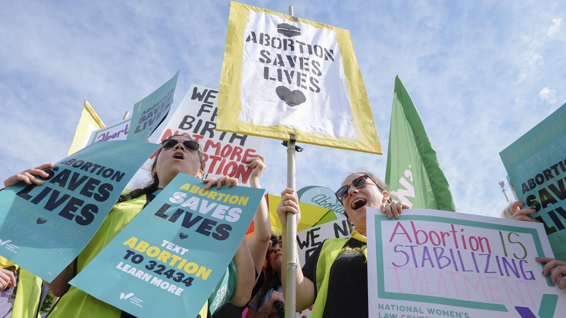 Aktivisten protestieren halten bunte Schilder mit der Aufschrift "ABORTION SAVES LIVES" und weiteren Forderungen für das Recht auf Abtreibung in den USA hoch