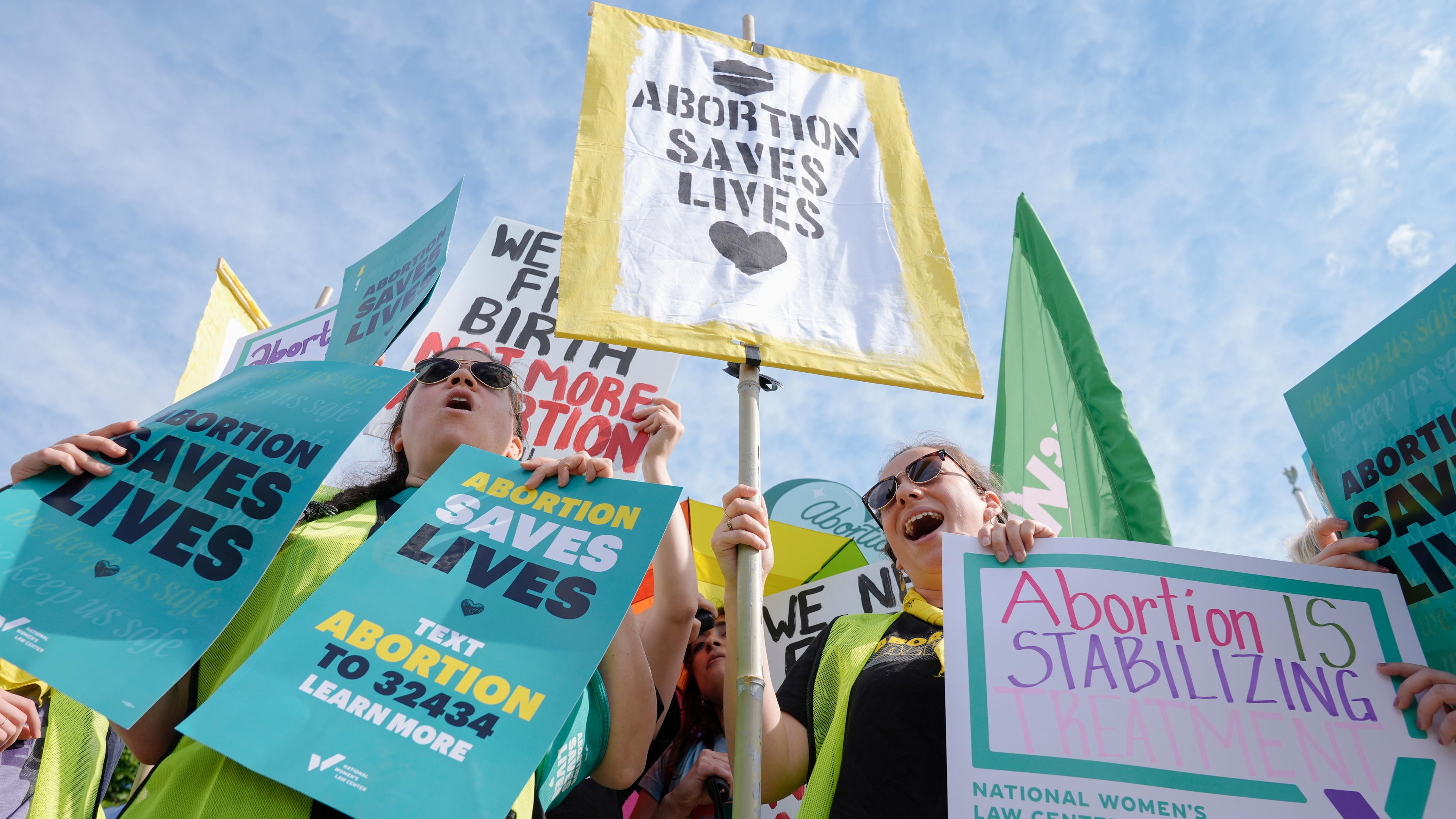 Aktivisten protestieren halten bunte Schilder mit der Aufschrift "ABORTION SAVES LIVES" und weiteren Forderungen für das Recht auf Abtreibung in den USA hoch