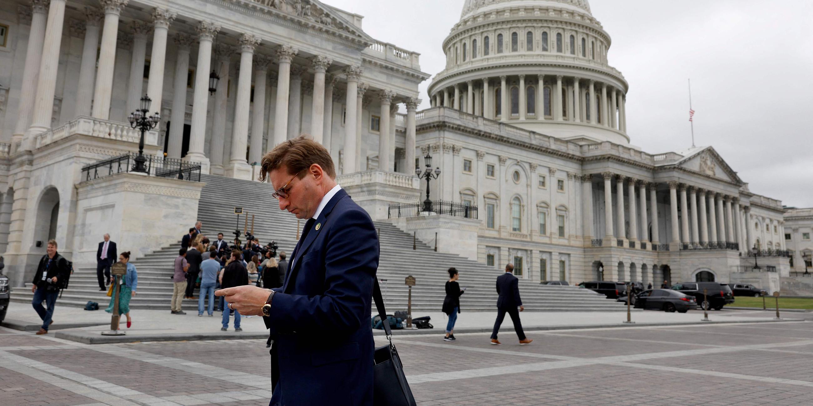 Abgeordneter blickt auf sein Telefon, als er das US-Kapitol in Washington, DC verlässt. 