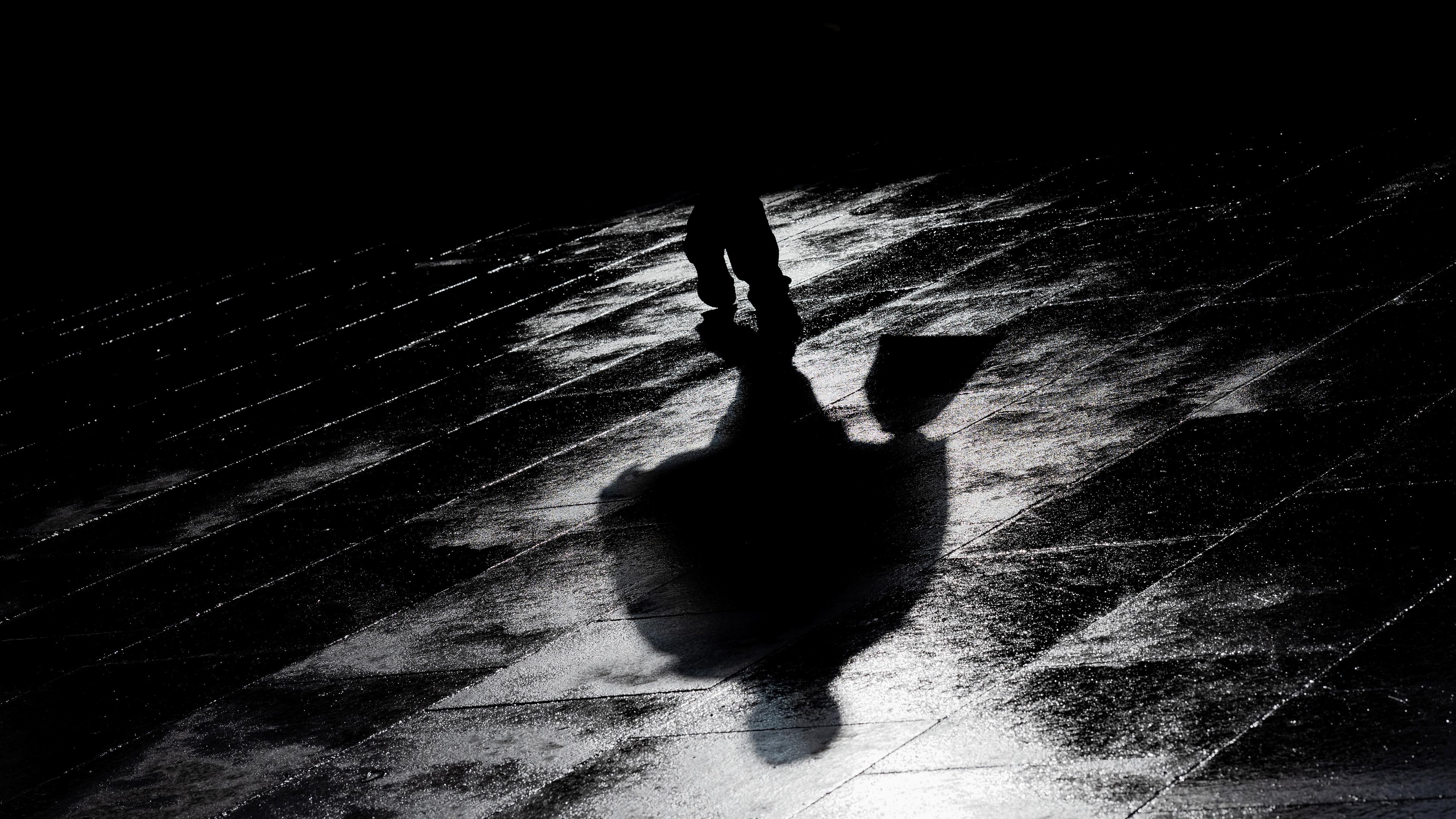 Ein Mann geht bei tief stehender Sonne über den regennassen Roncalli Platz