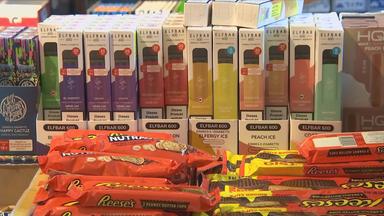 Verpackte Vapes füllen fast das gesamte Bild. Vorn stehen die schmalen Schachteln aufrecht in Pappaufstellern, dahinter sind weitere gestapelt. Auf den Verpackungen stehen die Marke Elfbar 600, unterschiedliche Geschmacksrichtungen und Nikotinangaben