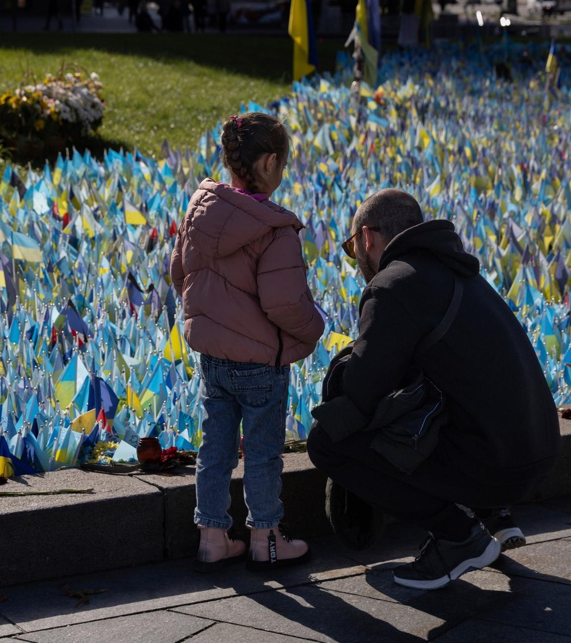 Auf dem Bild sind Familienmitglieder an einem Denkmal für ukrainische Soldaten zu sehen