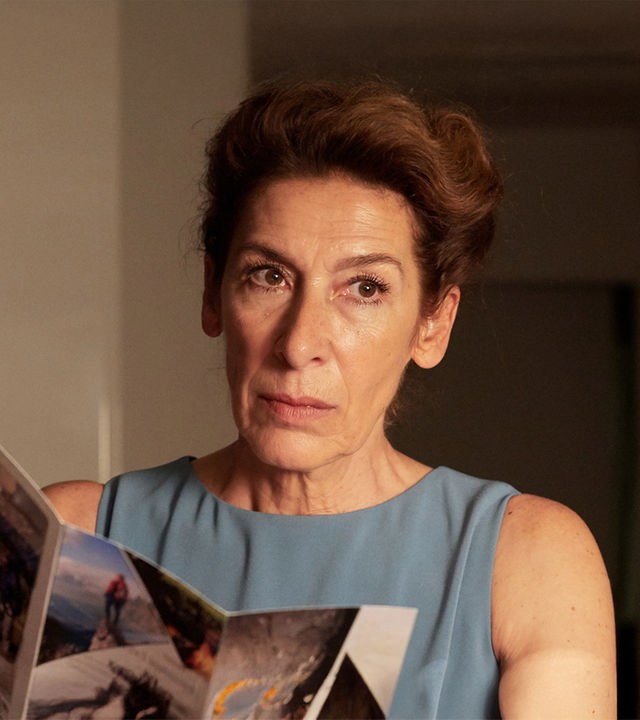 Gitti Kronlechner (Adele Neuhauser) liest in einem Prospekt und schaut nachdenklich.