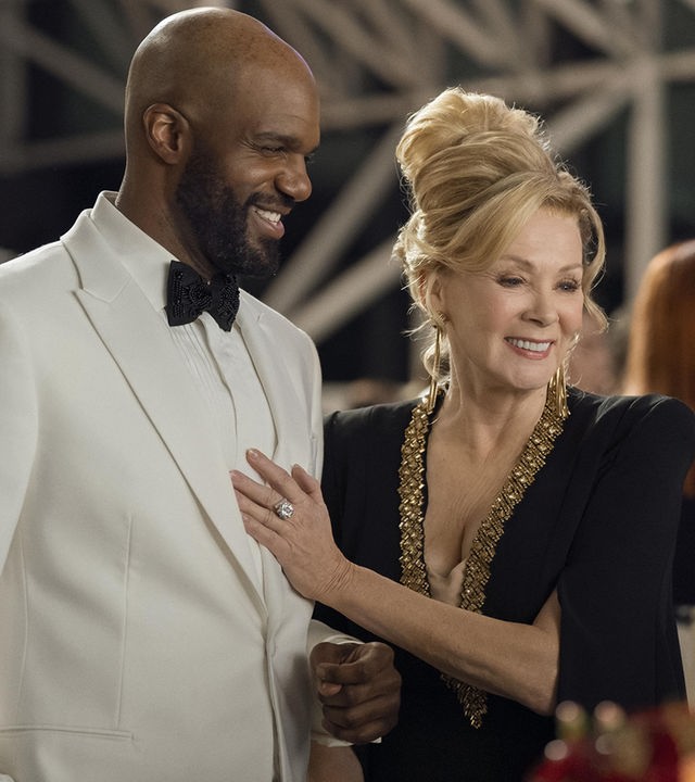 "Hacks - Verändere die Welt mit Lachern": Deborah (Jean Smart) steht im schicken Abendkleid neben dem mit weißen Smoking festlich gekleidetem Marcus (Carl Clemons-Hopkins). Deborah hat ihre Hand auf dessen Brust gelegt und beide lachen glücklich und gelöst. Im Hintergrund befinden sich weitere Personen (Komparsen).