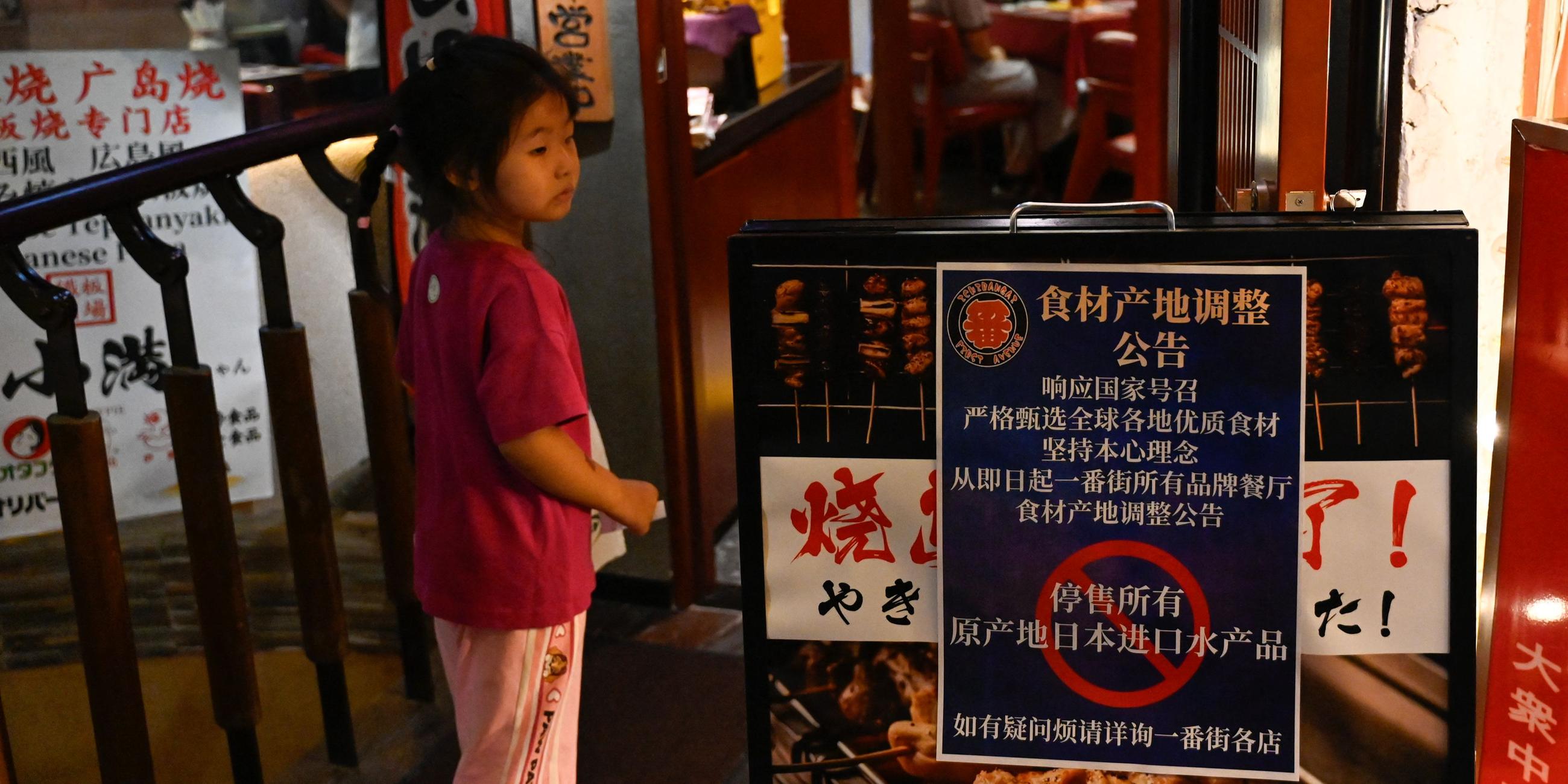 Ein Schild mit dem Hinweis "Verkauf aller aus Japan importierten Fischprodukte aussetzen" vor einem Restaurant in Pekind