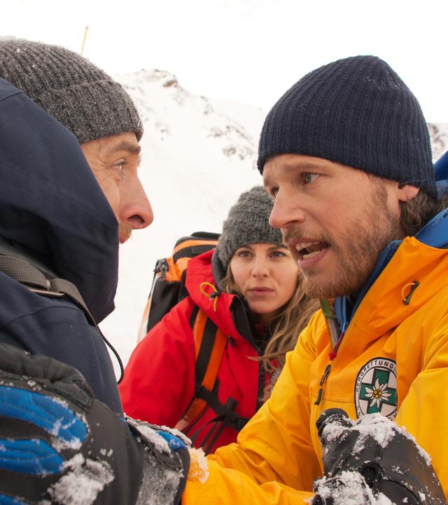 Die Bergretter Markus (Sebastian Ströbel, r.) und Katharina (Luise Bähr, M.) versuchen, den aufgebrachten Chris Haffner (Gabriel Raab, l.) zu beruhigen.