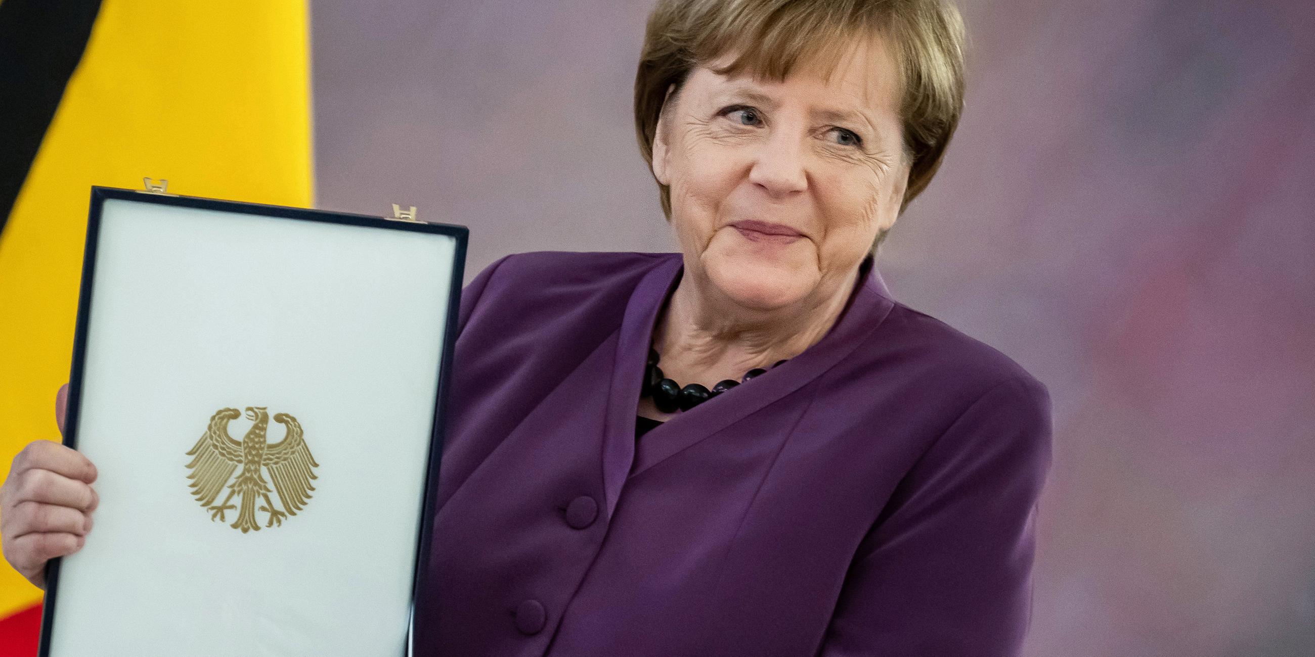Berlin: Angela Merkel, (CDU), ehemalige Bundeskanzlerin, hält das Großkreuz des Verdienstordens der Bundesrepublik Deutschland in besonderer Ausführung während einer Zeremonie im Schloss Bellevue.