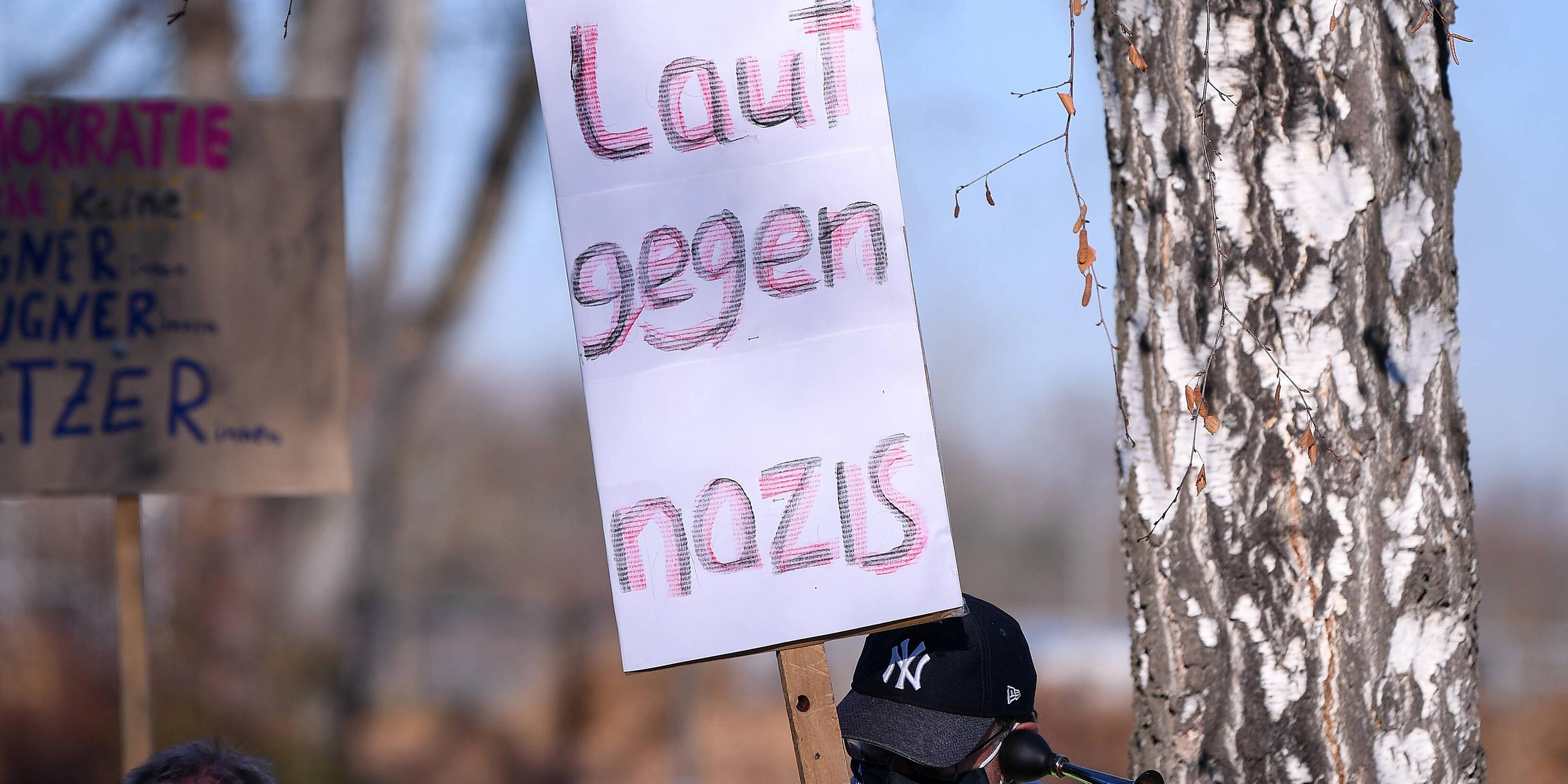 Ein Man hält ein Schild mit der aufschrift "laut gegen Nazis" hoch bei eine Kundgebung am 28.22.2020 in Rottenburg