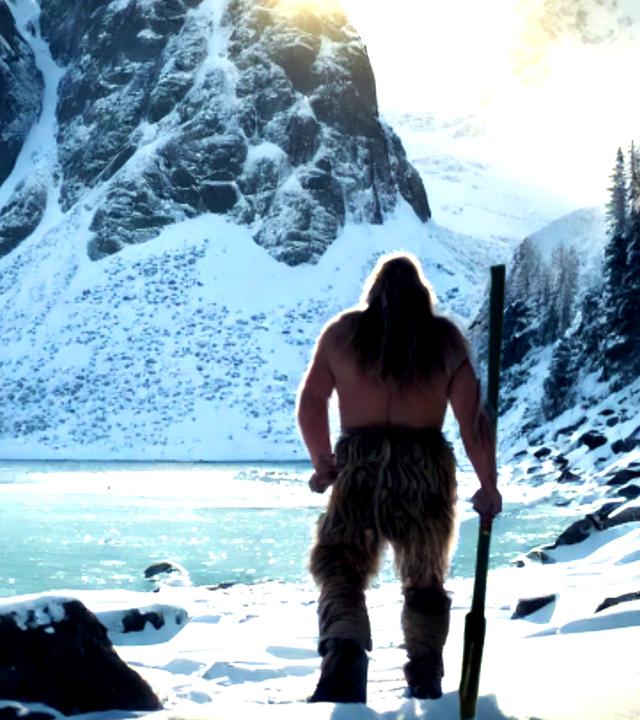 Ein Steinzeitmensch blickt auf eine bergige Winterlandschaft. Im Hintergrund ist der Himmel grün eingefärbt.