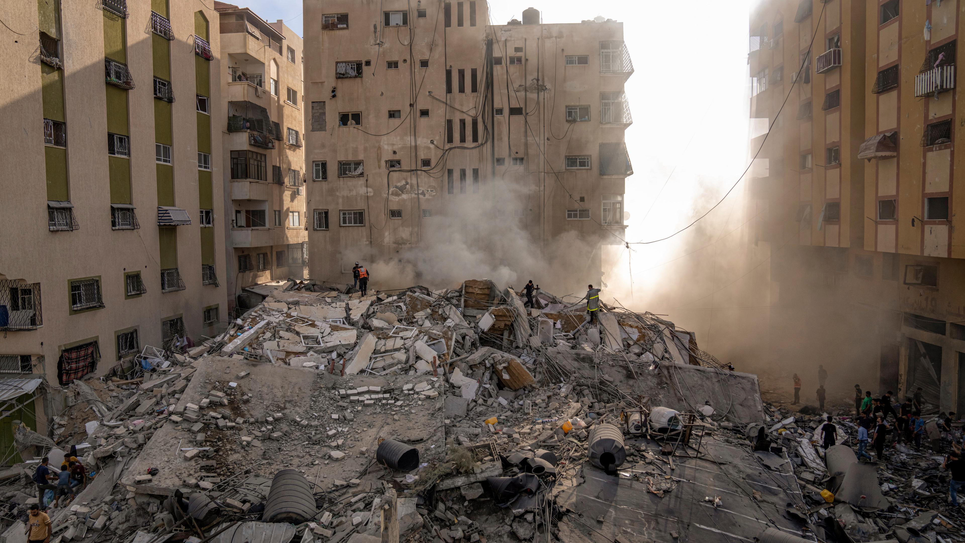 Palestinians inspect the rubble of a building after it was struck by an Israeli airstrike, in Gaza City, Saturday, Oct. 7, 2023. 