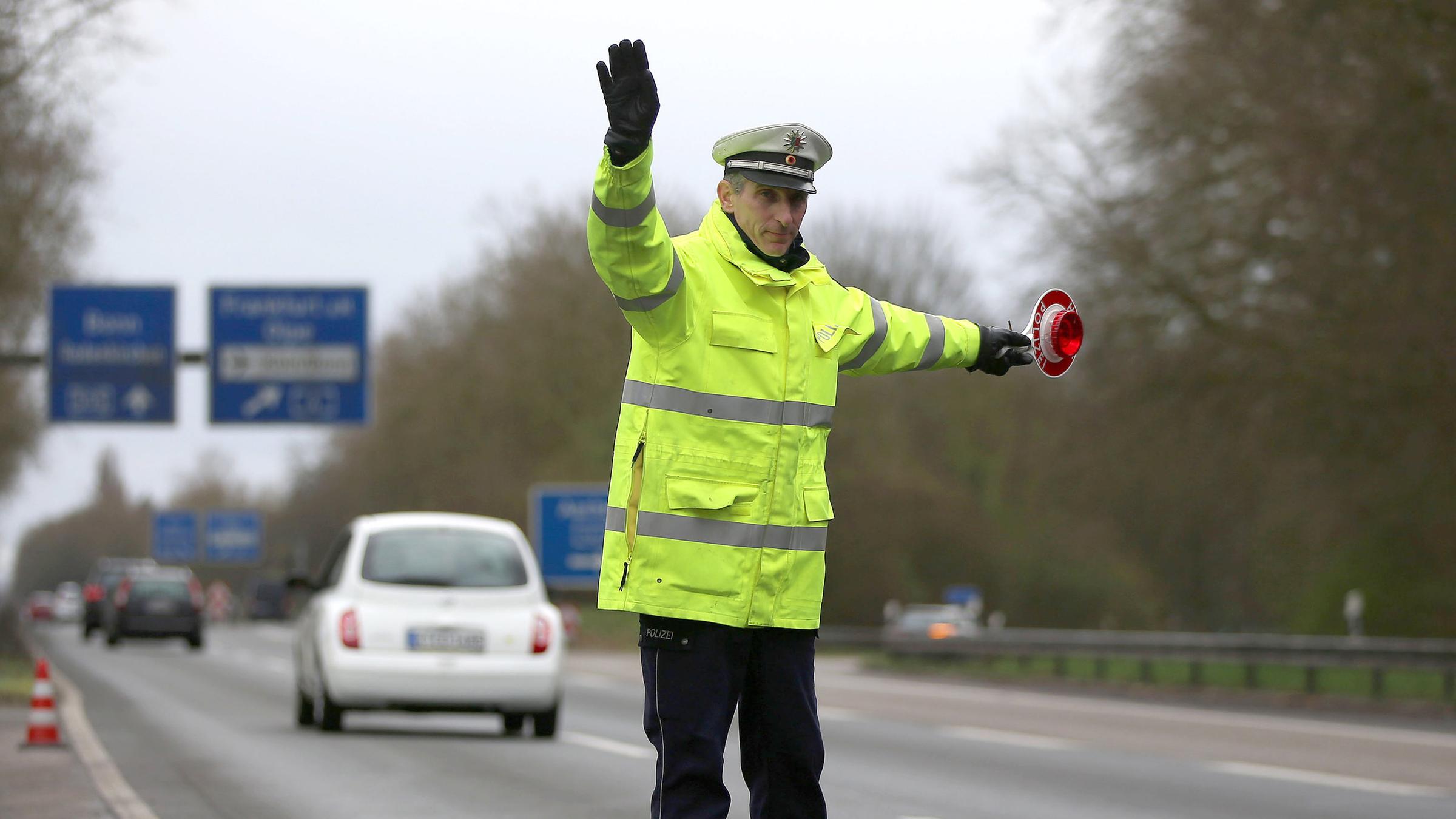 Ein Polizist winkt am 21.03.2017 auf der Autobahn 555 bei Köln (Nordrhein-Westfalen) Fahrzeuge zur Kontrolle raus