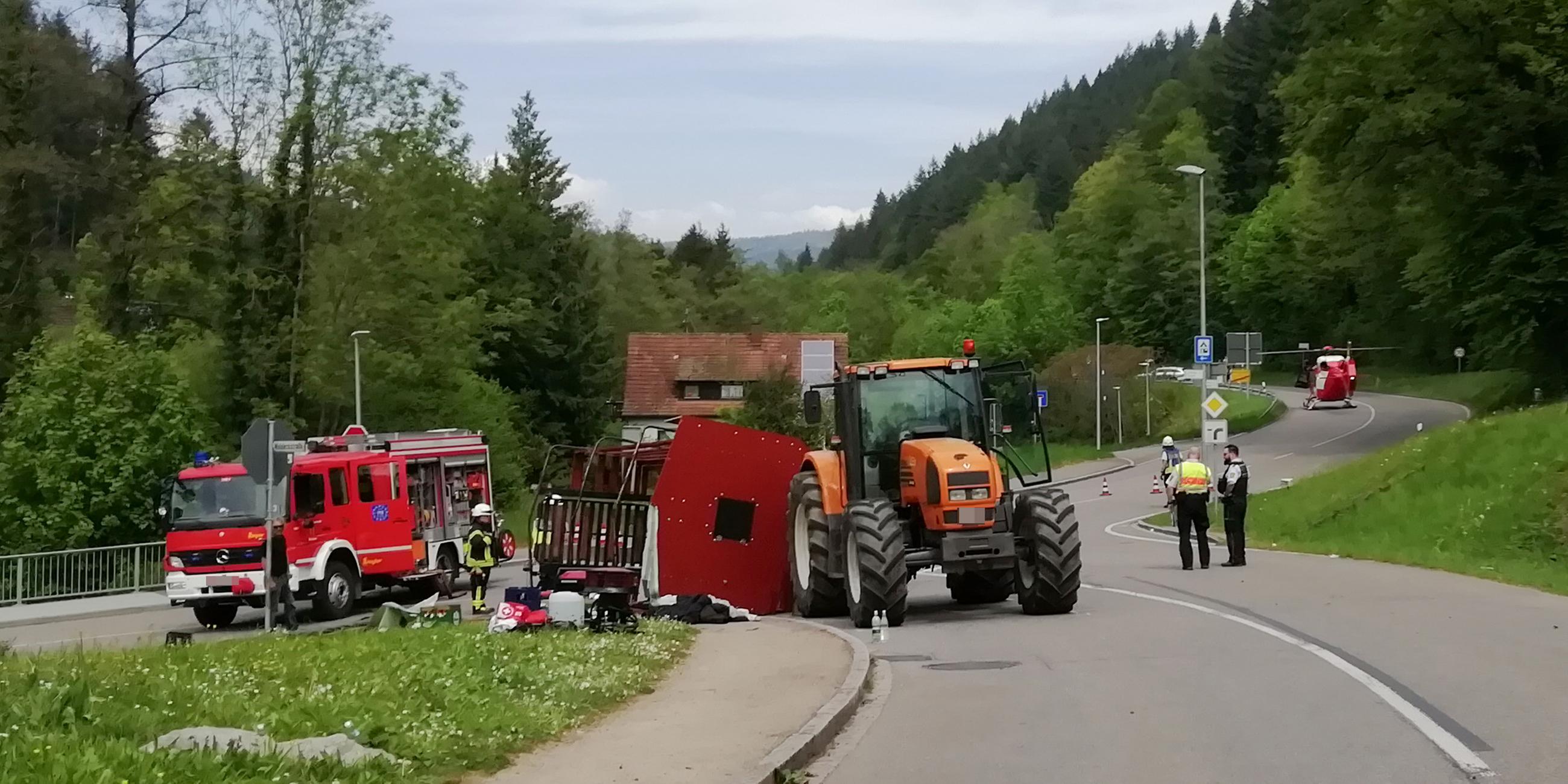 Baden-Württemberg, Kandern: Rettungskräfte stehen nach einem Unfall neben einem einem umgestürzten Maiwagen.