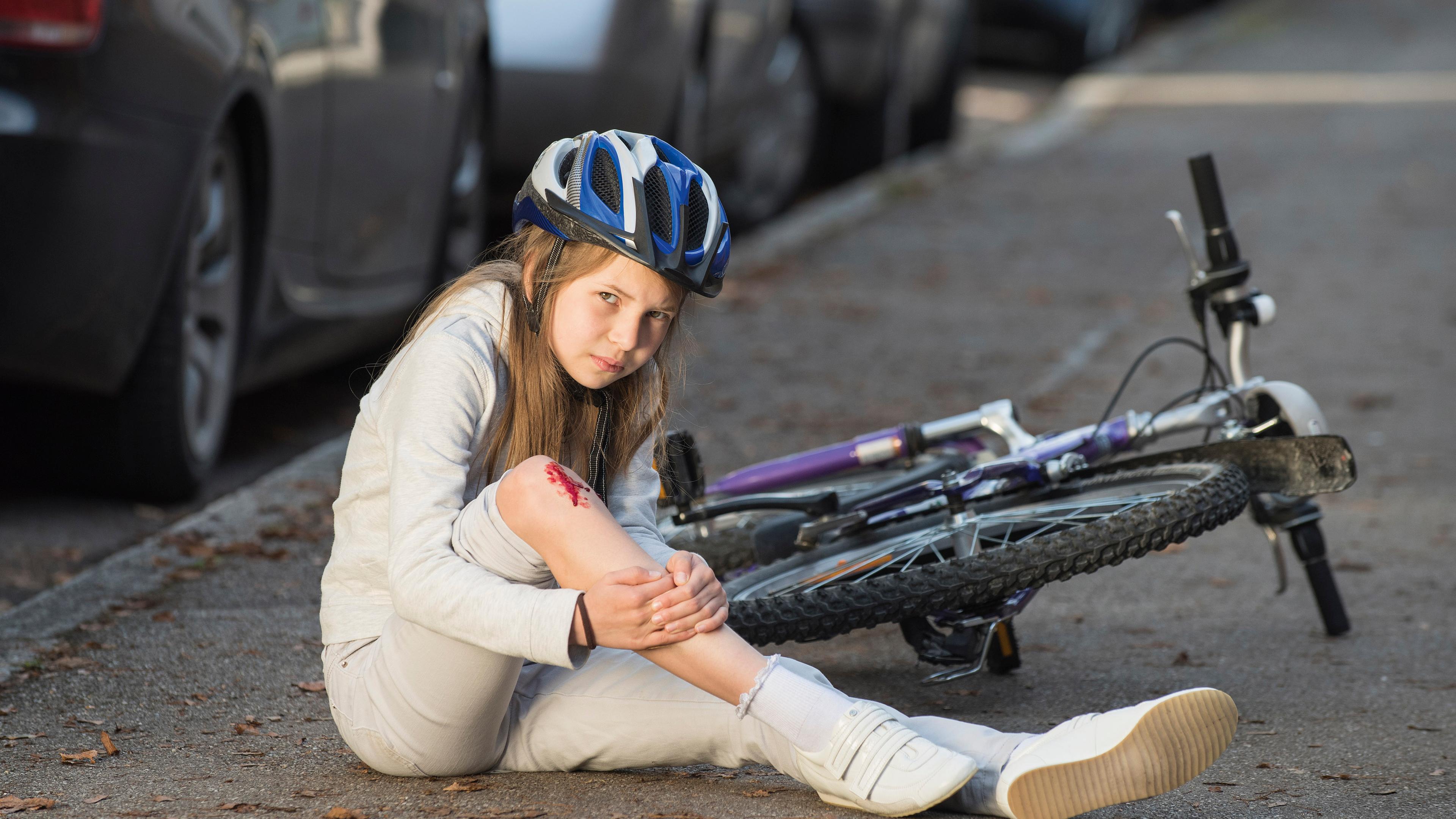 Mädchen mit Verletzung am Knie beim Fahrradfahren