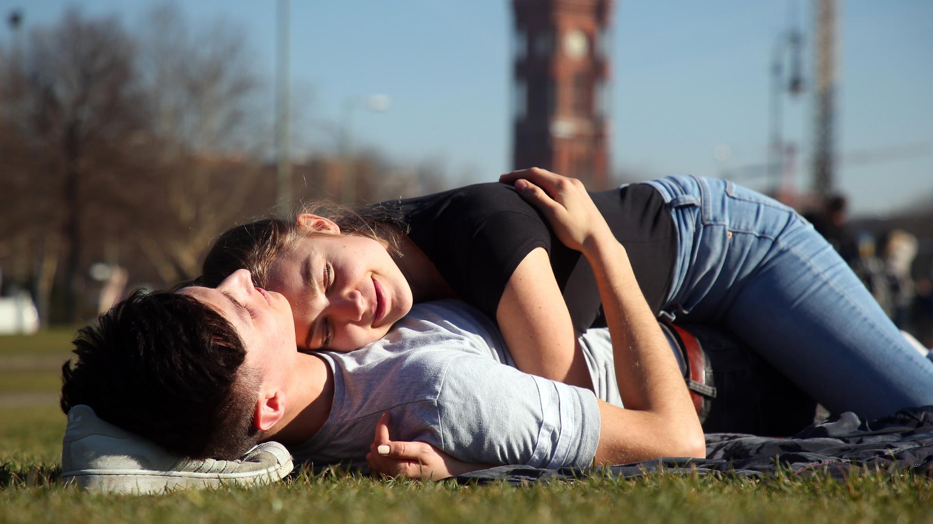 Ein verliebtes Paar liegt umschlungen auf einer Wiese in Berlin
