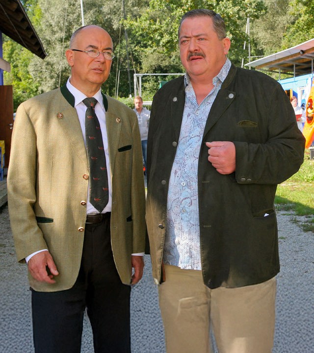 "Die Rosenheim-Cops - Vertrauen ist gut, Kontrolle ist besser": Polizeichef Achtziger (Alexander Duda) und Kommissar Hofer (Joseph Hannesschläger) stehen nebeneinander auf einem Weg im Ruderverein und besprechen sich.