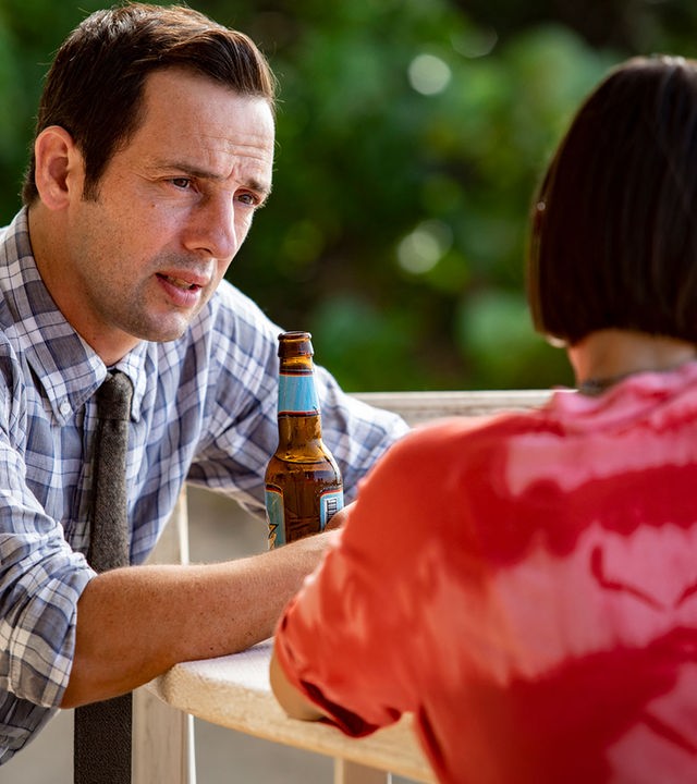 "Death in Paradise - Verwaschene Spuren": Neville (Ralf Little) sitzt mit Izzy (Kate O’Flynn) an einem Tisch und schaut sie verständnisvoll an.
