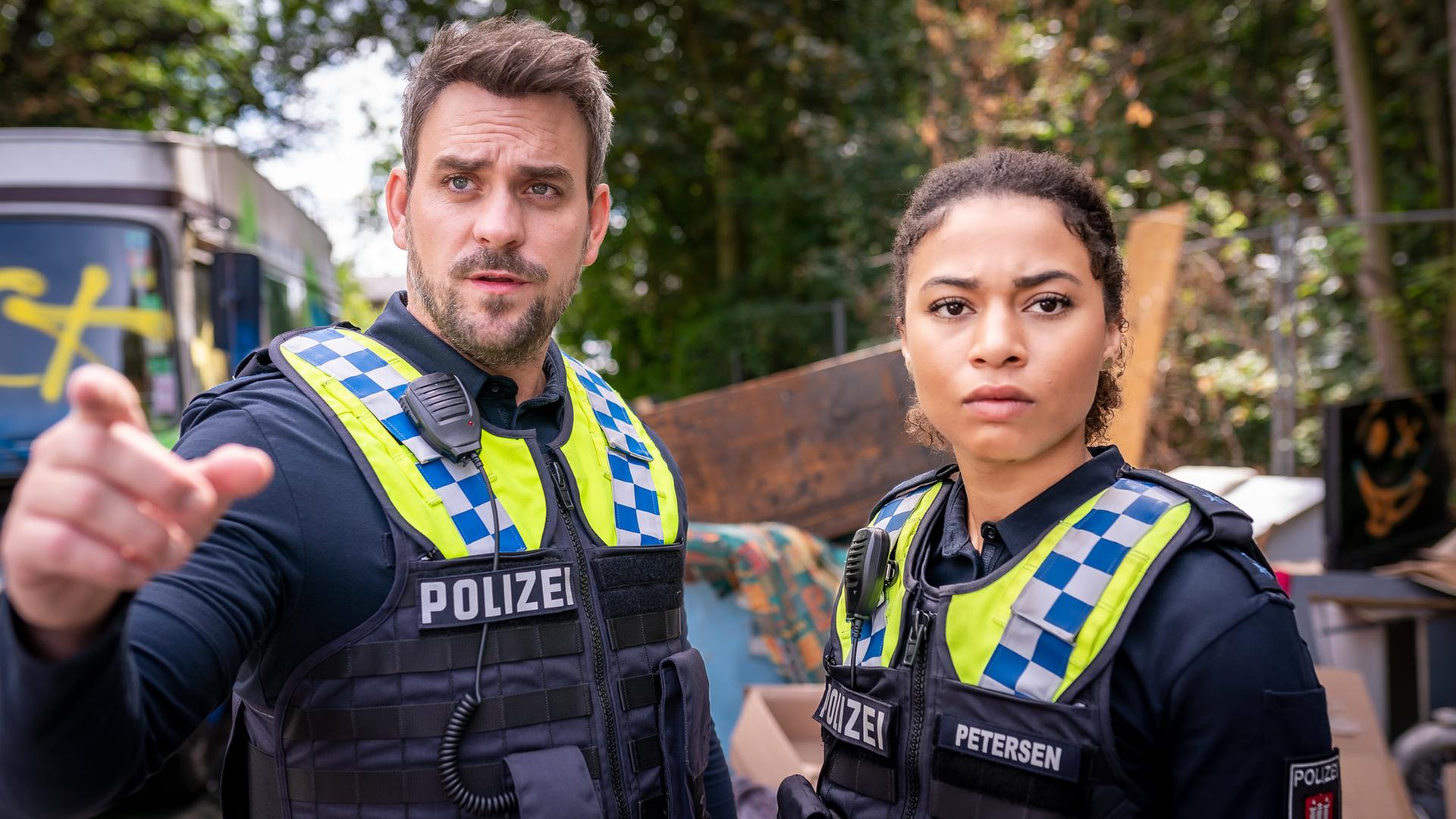 "Notruf Hafenkante - Verzweifelt": Großaufnahme des Polizisten Kris Freiberg (Marc Barthel) und dessen Kollegin Daisy Petersen (Aysha Joy Samuel). Sie stehen dicht nebeneinander und blicken in eine Richtung.