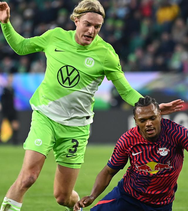 Wolfsburgs Sebastiaan Bornauw (l) bringt Leipzigs Lois Openda im Strafraum zu Fall.