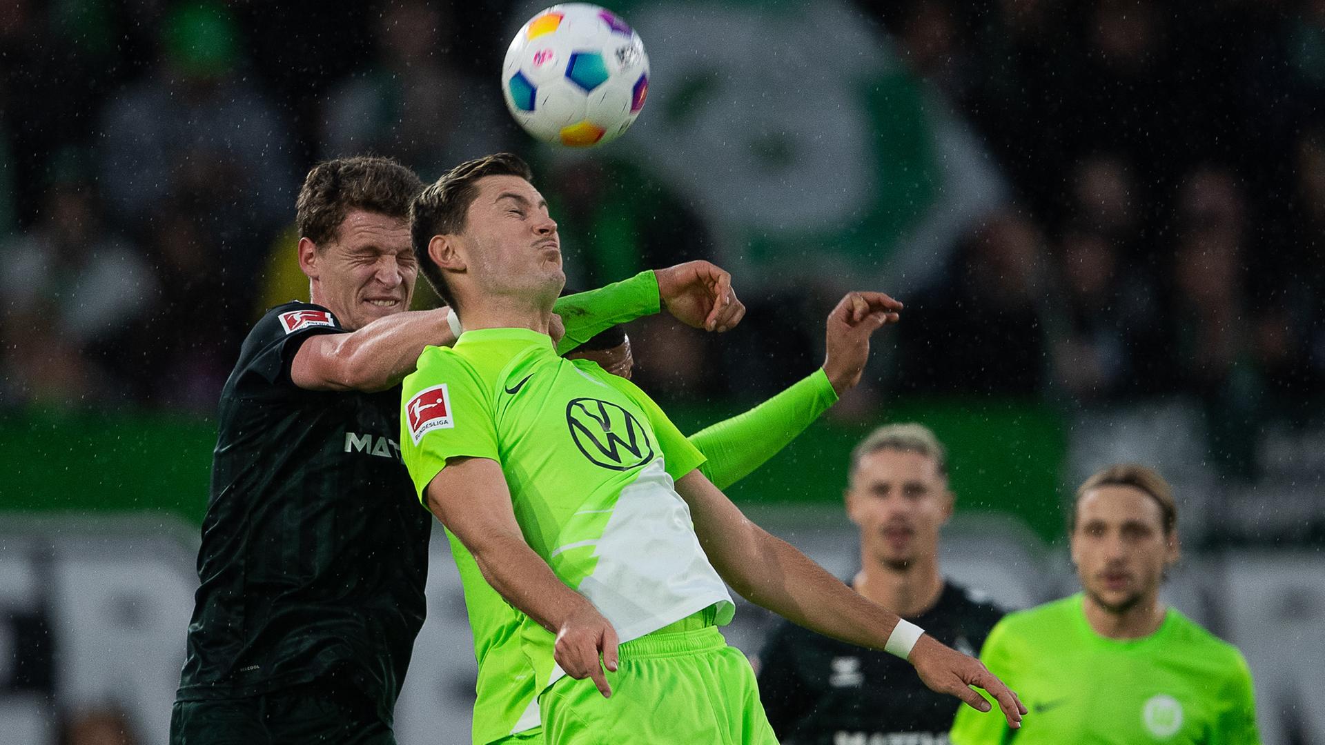 Wolfsburgs Jonas Wind (r) spielt gegen Bremens Mitchell Weiser.