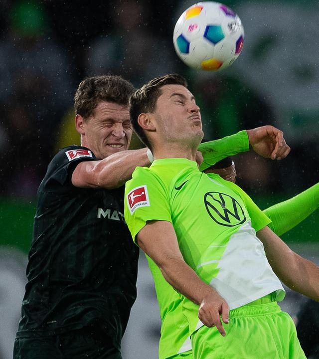 Wolfsburgs Jonas Wind (r) spielt gegen Bremens Mitchell Weiser.