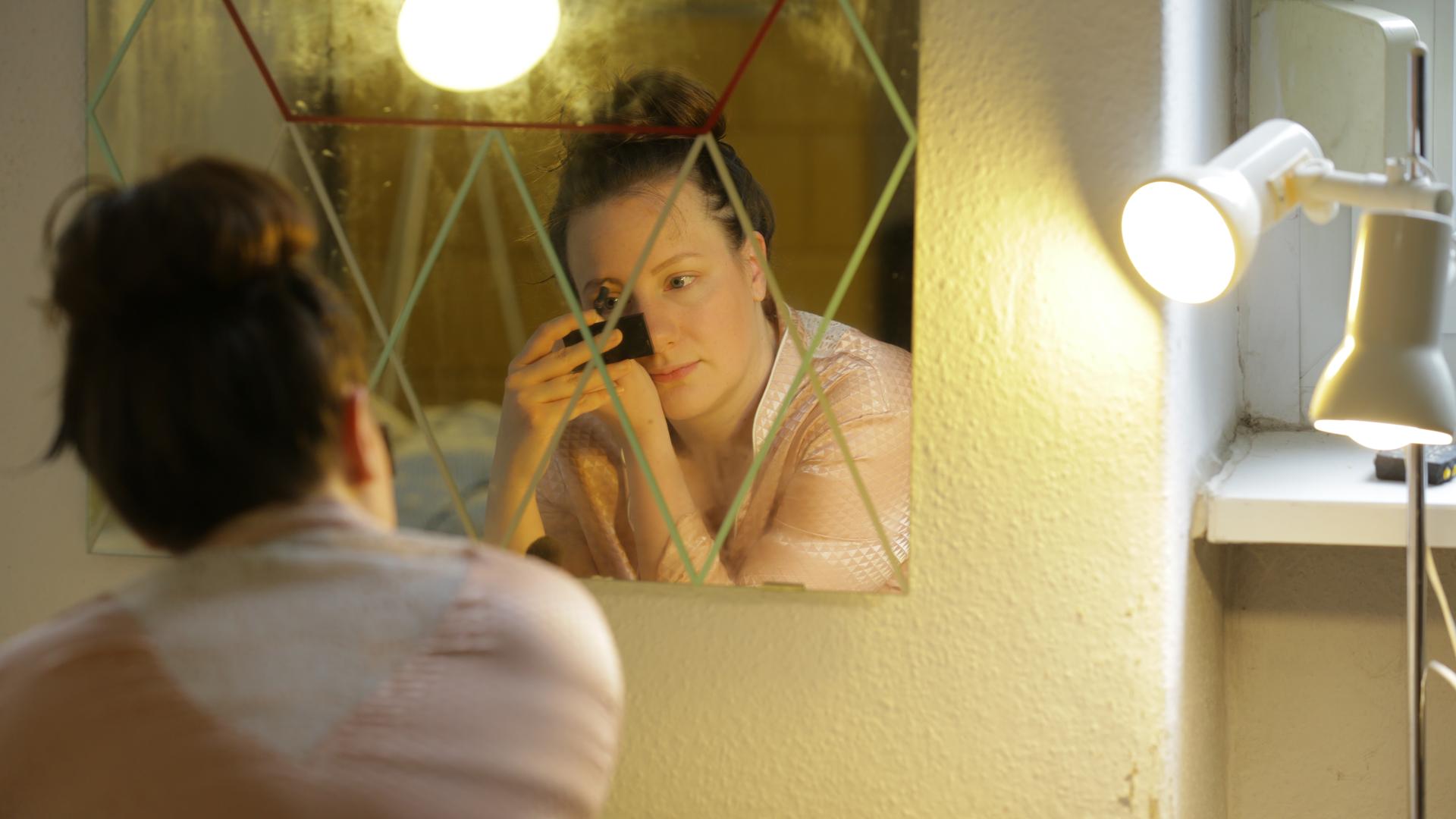 Jana schminkt sich vor dem Spiegel