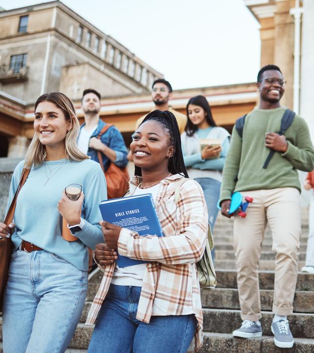 Mehrere Personen bewegen sich gemeinsam im Außenbereich eines Gebäudes eine Treppe hinunter, einige tragen Bücher und Unterlagen bei sich. Die Darstellung steht für ein diverses Miteinander in Bildung und Arbeitsumfeld.