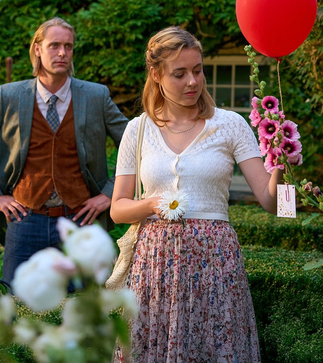 Joey (Bernd-Christian Althoff) steht mit Gwen (Meriel Hinsching) im Garten. Gwen hält einen roten Luftballon mit einer angebrachten Nachricht in der Hand.