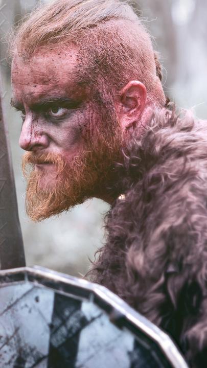 Montage: Links eine alte Tafel mit Wikingerrunen; Rechts ein entschlossen blickender Wikinger mit Schwert und Schild.