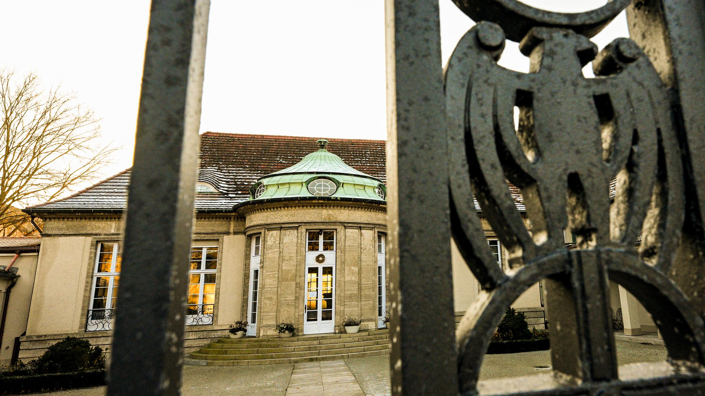 Villa hinter gussseisernem Tor mit Adler-Emblem.